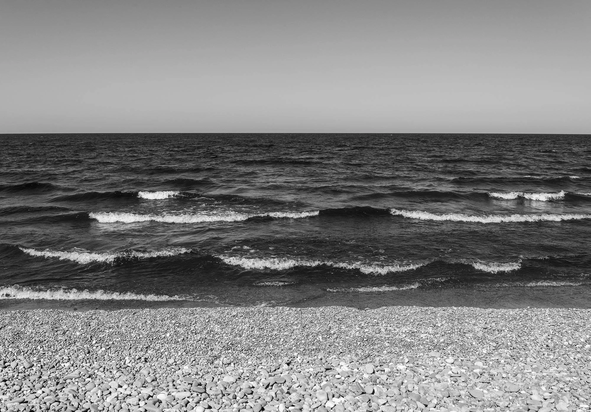 Black and white photograph of beach, water/waves and sky