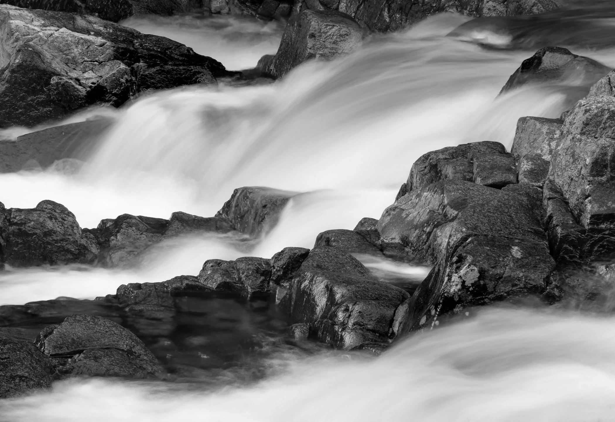 black and white photograph of water crashing into and through rocks
