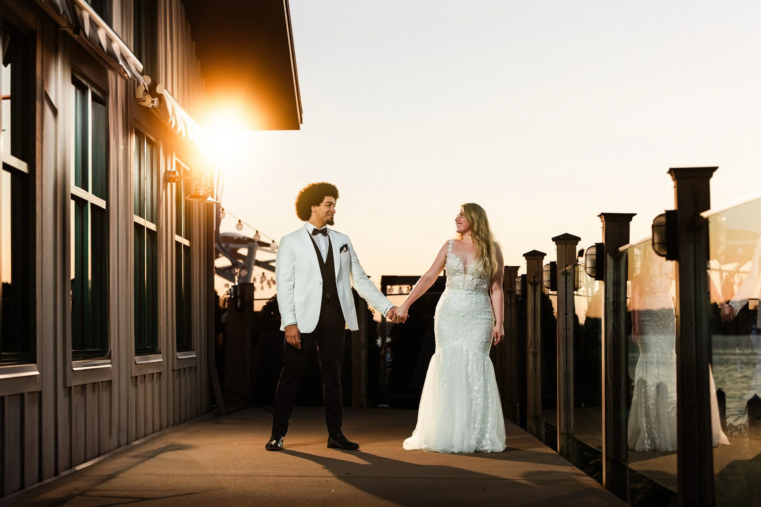 bride and groom holding hands looking at each other during sunset