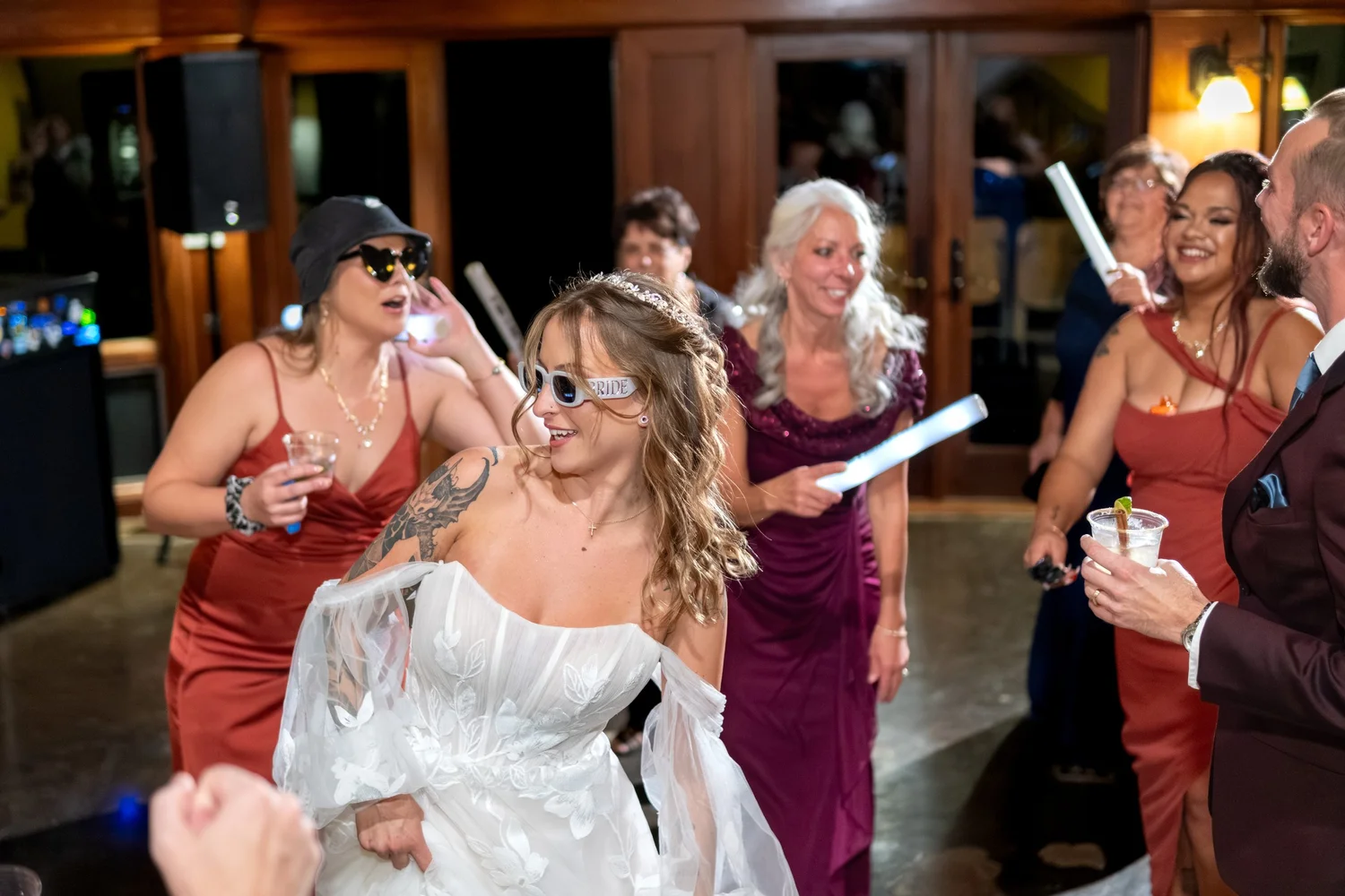 Sarah bride in BRIDE sunglasses dancing with bridesmaids glow sticks SkiEsta reception Newry Maine fall wedding VMG Productions
