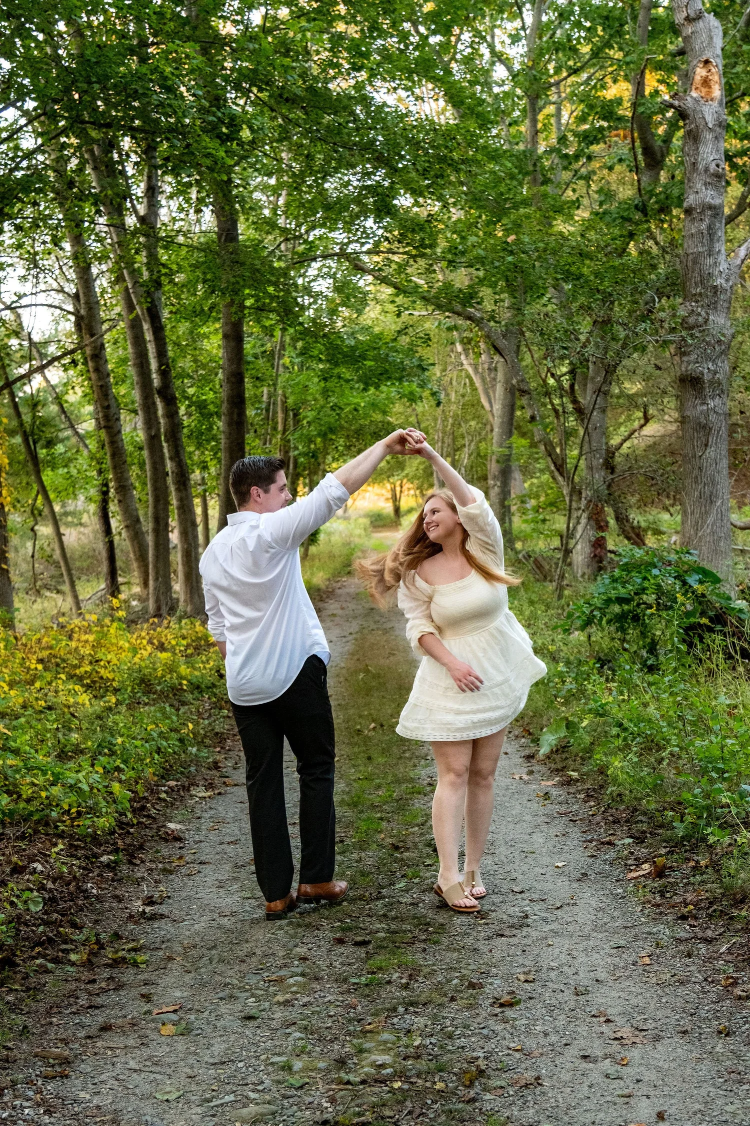 Kayla and Ethan engaged couple twirling on forest path Odiorne Point State Park New Hampshire engagement session photography VMG Productions