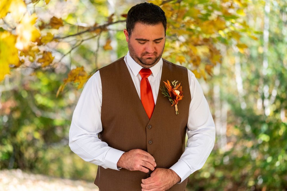 Joshua adjusting vest outdoors before fall ceremony at The Watson Homestead Hiram Maine fall wedding photography VMG Productions
