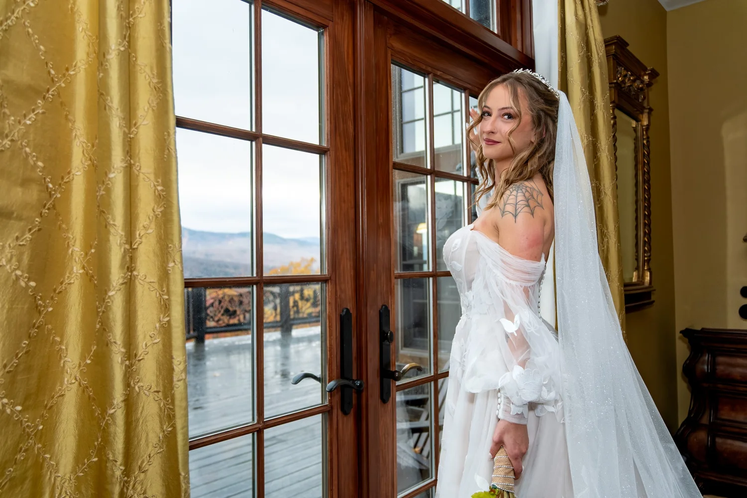 Sarah bride in wedding gown by French doors inside SkiEsta lodge mountain view Newry Maine fall wedding VMG Productions