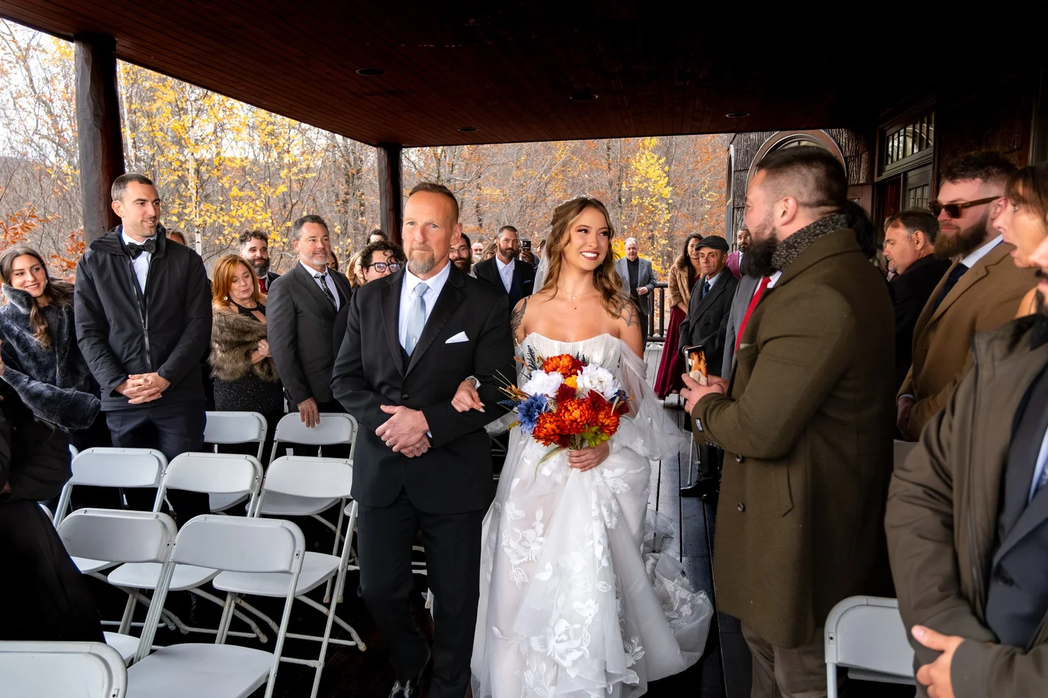 Sarah processional walking down aisle with father guests watching SkiEsta Newry Maine fall wedding VMG Productions