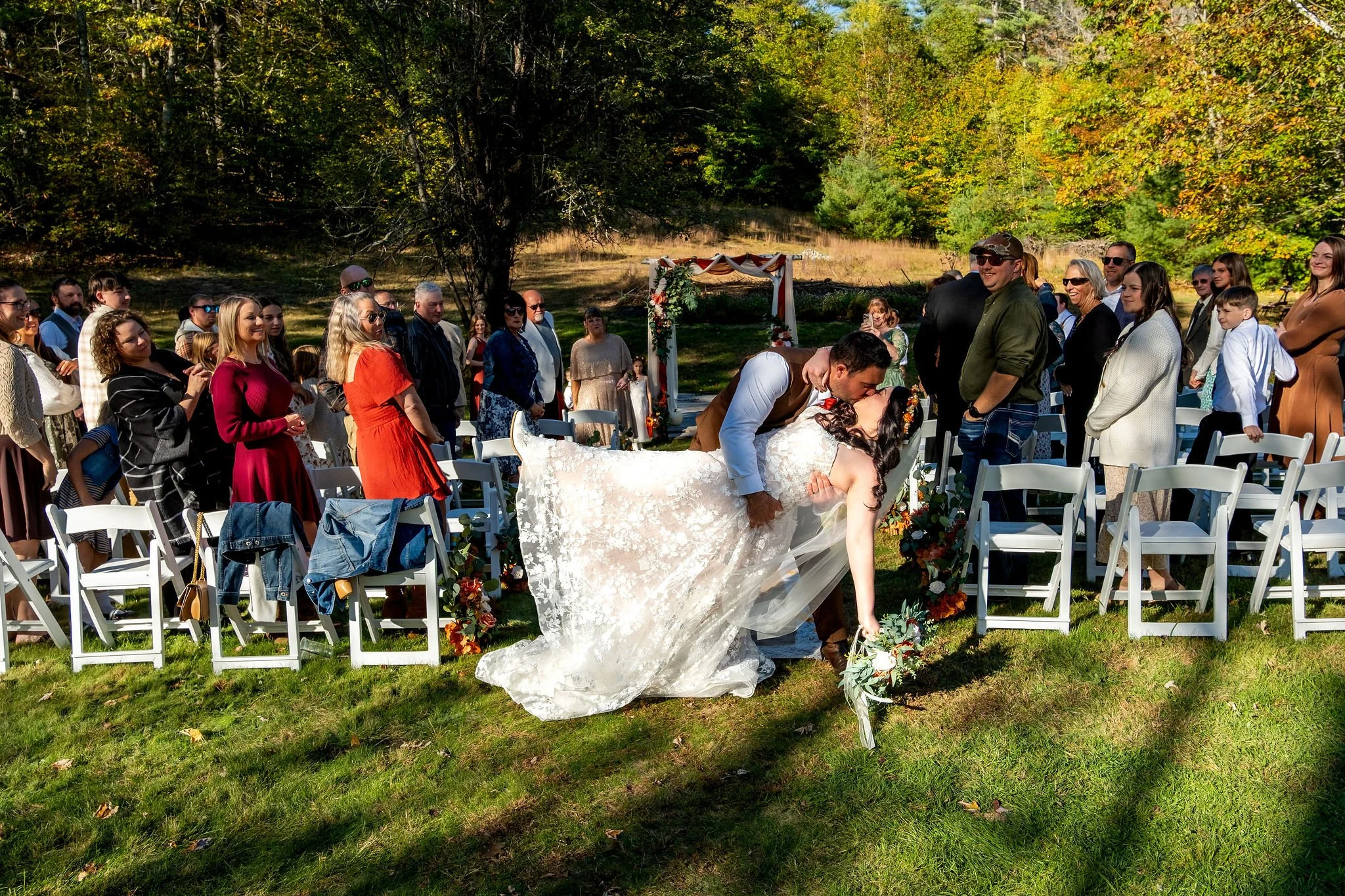 Meagan and Joshua dipping for ceremony recessional kiss at The Watson Homestead Hiram Maine fall wedding photography VMG Productions