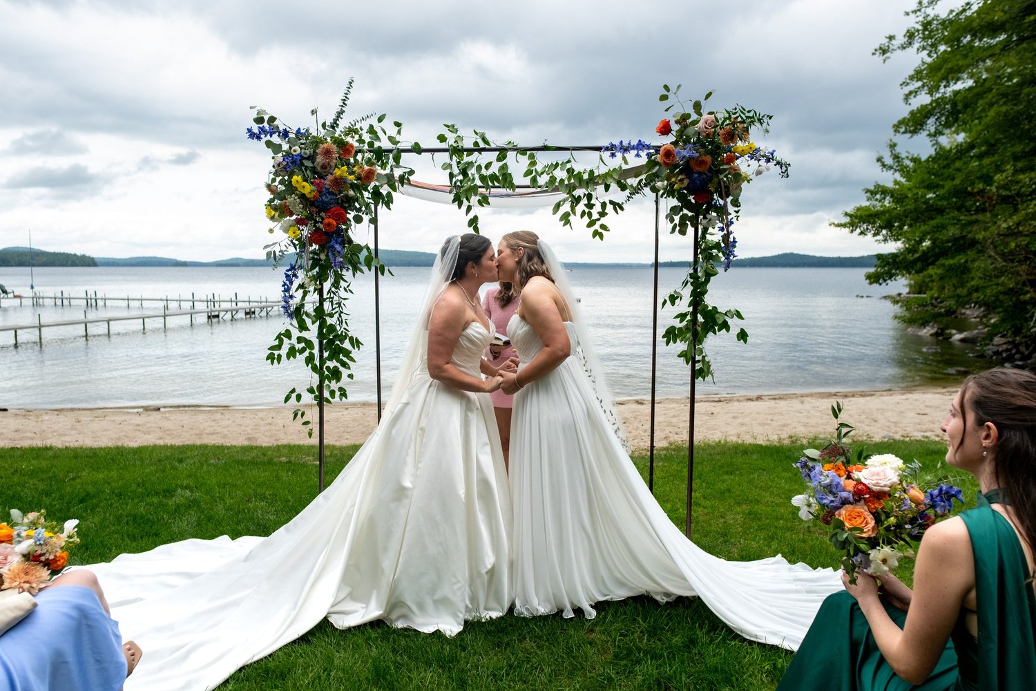 First kiss under a floral chuppah beside the lake at Camp Runoia in Belgrade Maine