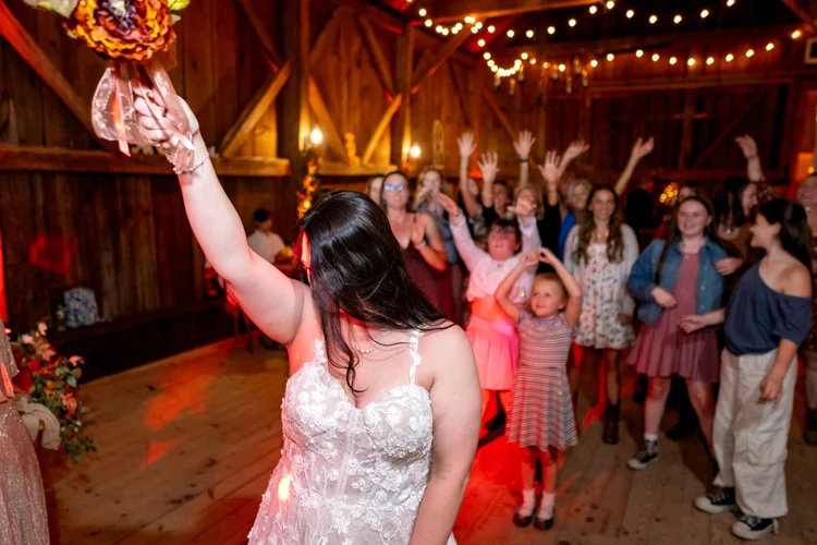 Meagan bouquet toss in barn reception at The Watson Homestead Hiram Maine fall wedding photography VMG Productions