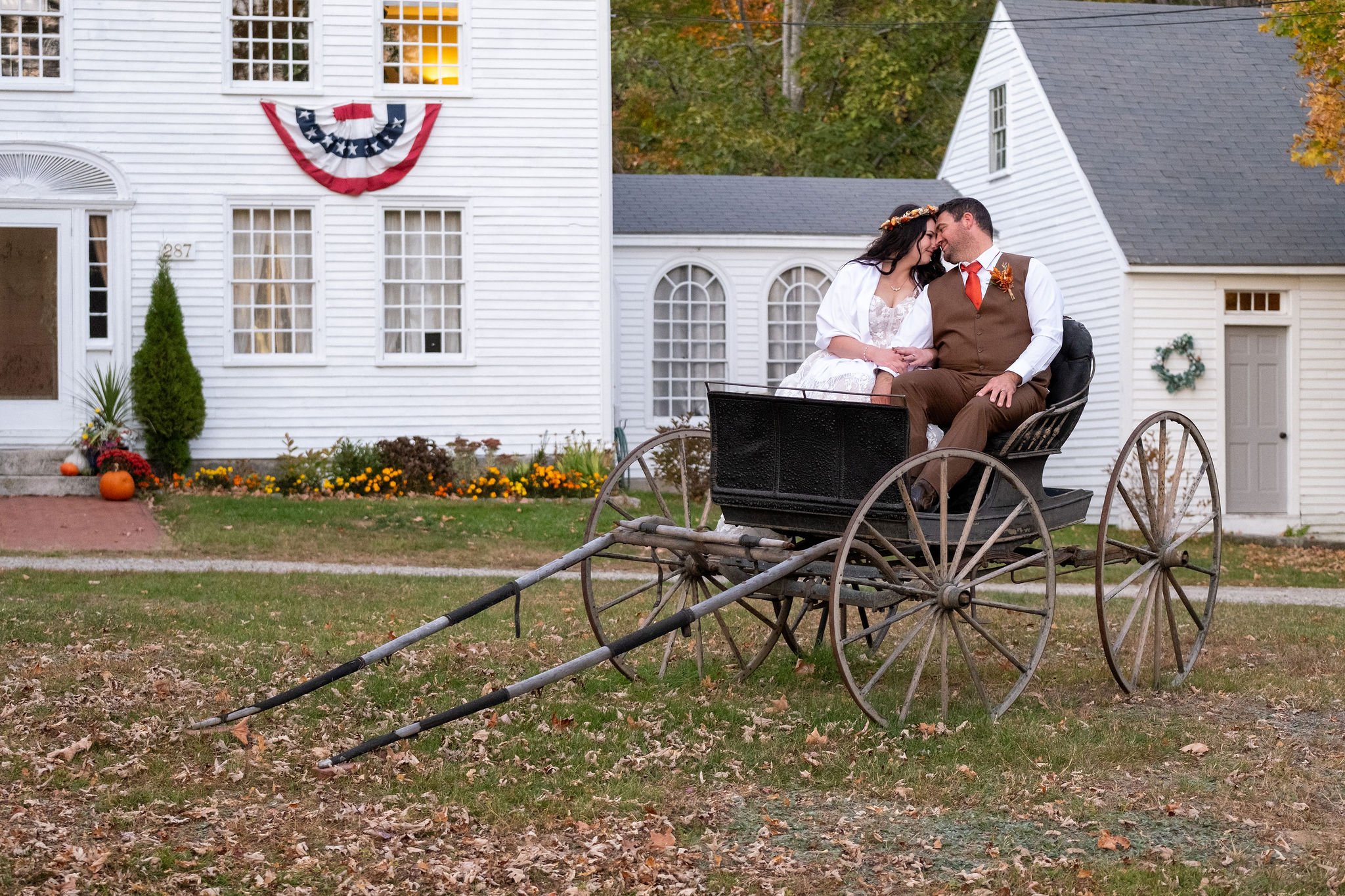 Meagan and Joshua sitting in antique wagon at The Watson Homestead Hiram Maine fall wedding photography VMG Productions