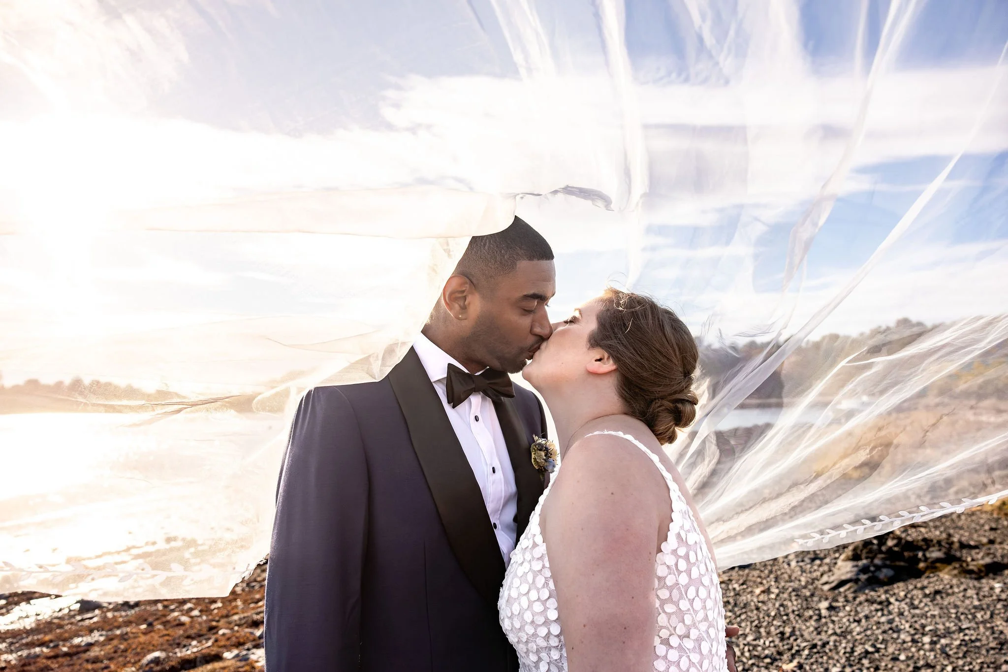 Kaitlyn and Darren kissing with veil flowing in coastal breeze Nonantum Resort Kennebunkport Maine fall wedding photography VMG Productions
