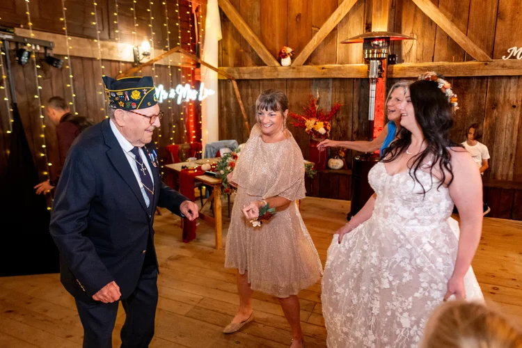 Meagan dancing with guests in rustic barn reception at The Watson Homestead Hiram Maine fall wedding photography VMG Productions