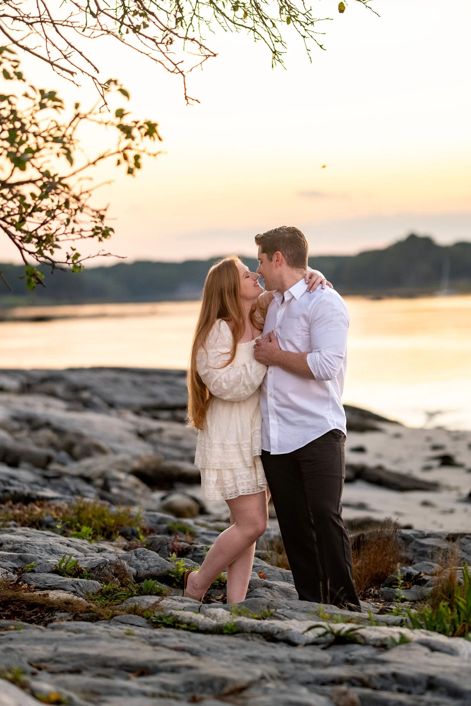 Kayla and Ethan engaged couple embracing rocky shoreline sunset coastal Odiorne Point State Park New Hampshire engagement photography VMG Productions