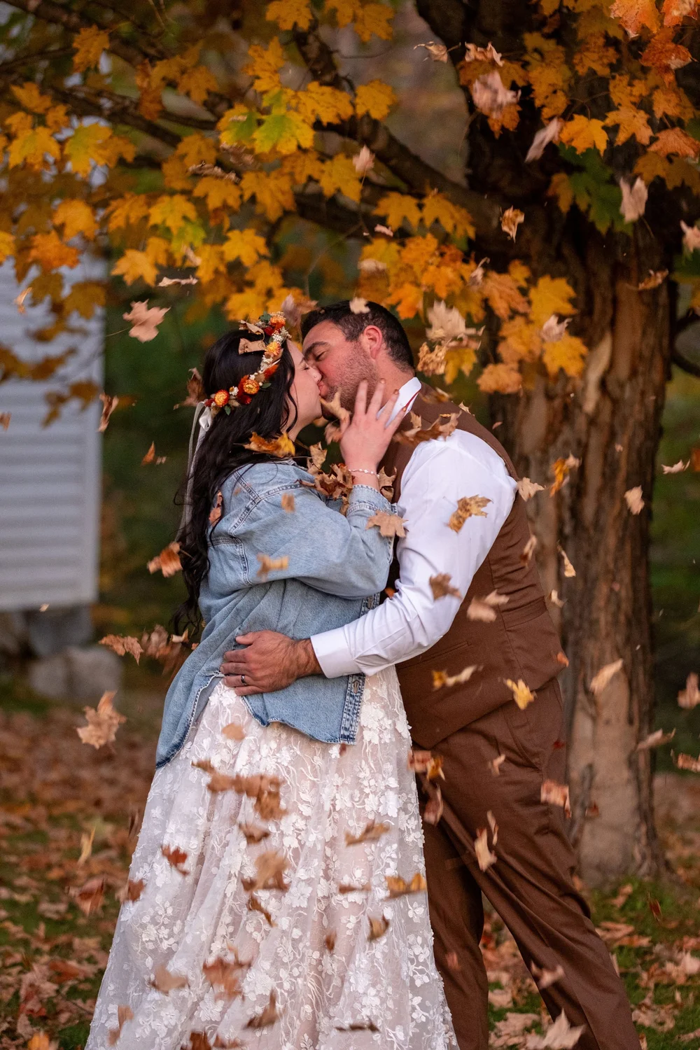 Meagan and Joshua kissing under falling leaves at The Watson Homestead Hiram Maine fall wedding photography VMG Productions