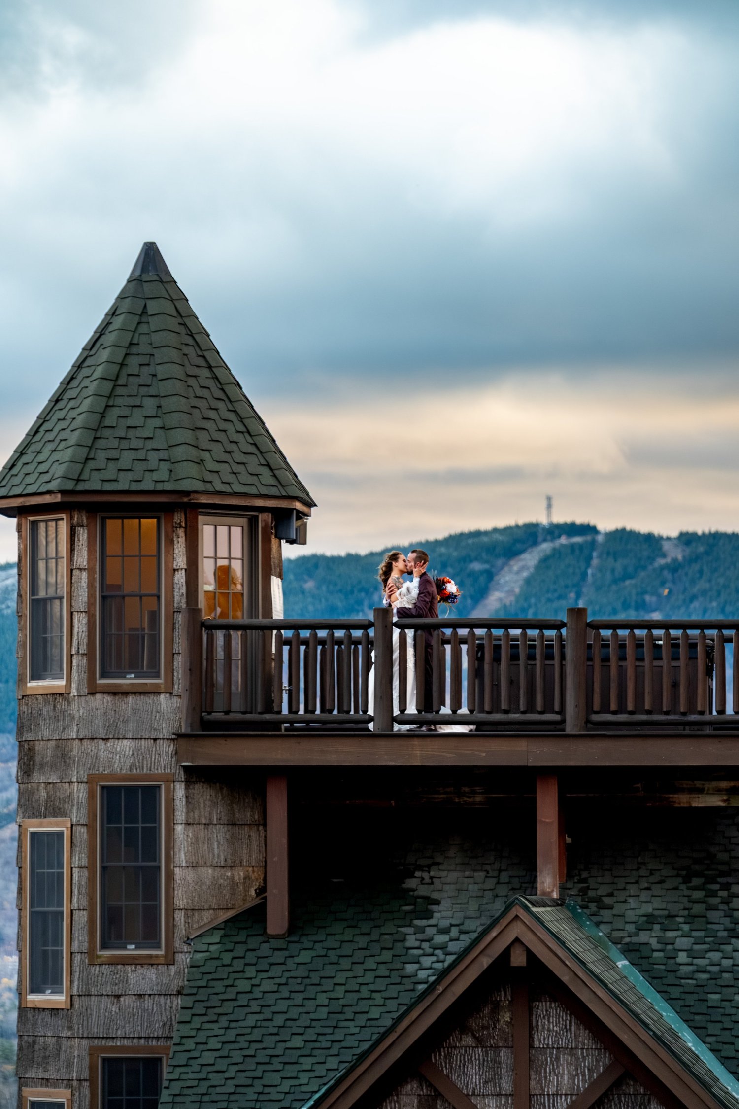 Sarah and Steve kissing on SkiEsta castle tower balcony mountain backdrop Newry Maine fall wedding portrait VMG Productions