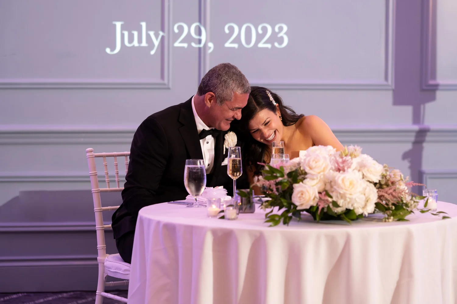 Nicole and Alexey laughing together at their sweetheart table at Portland Sheraton at Sable Oaks South Portland Maine summer wedding photography VMG Productions