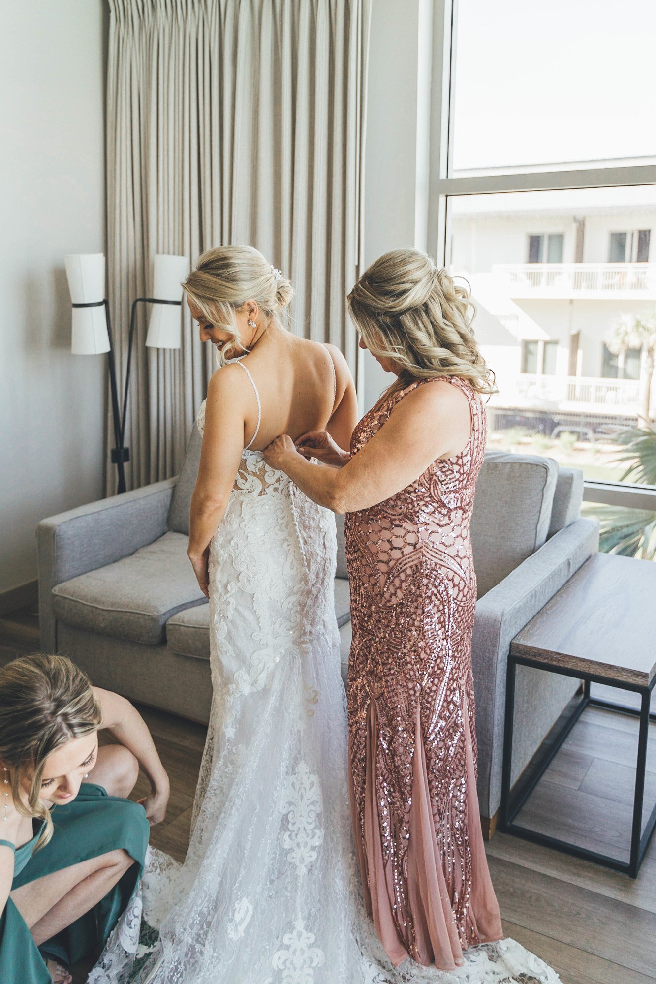 Southern Palms Studio bride is assisted into dress by mother and maid of honor.jpg