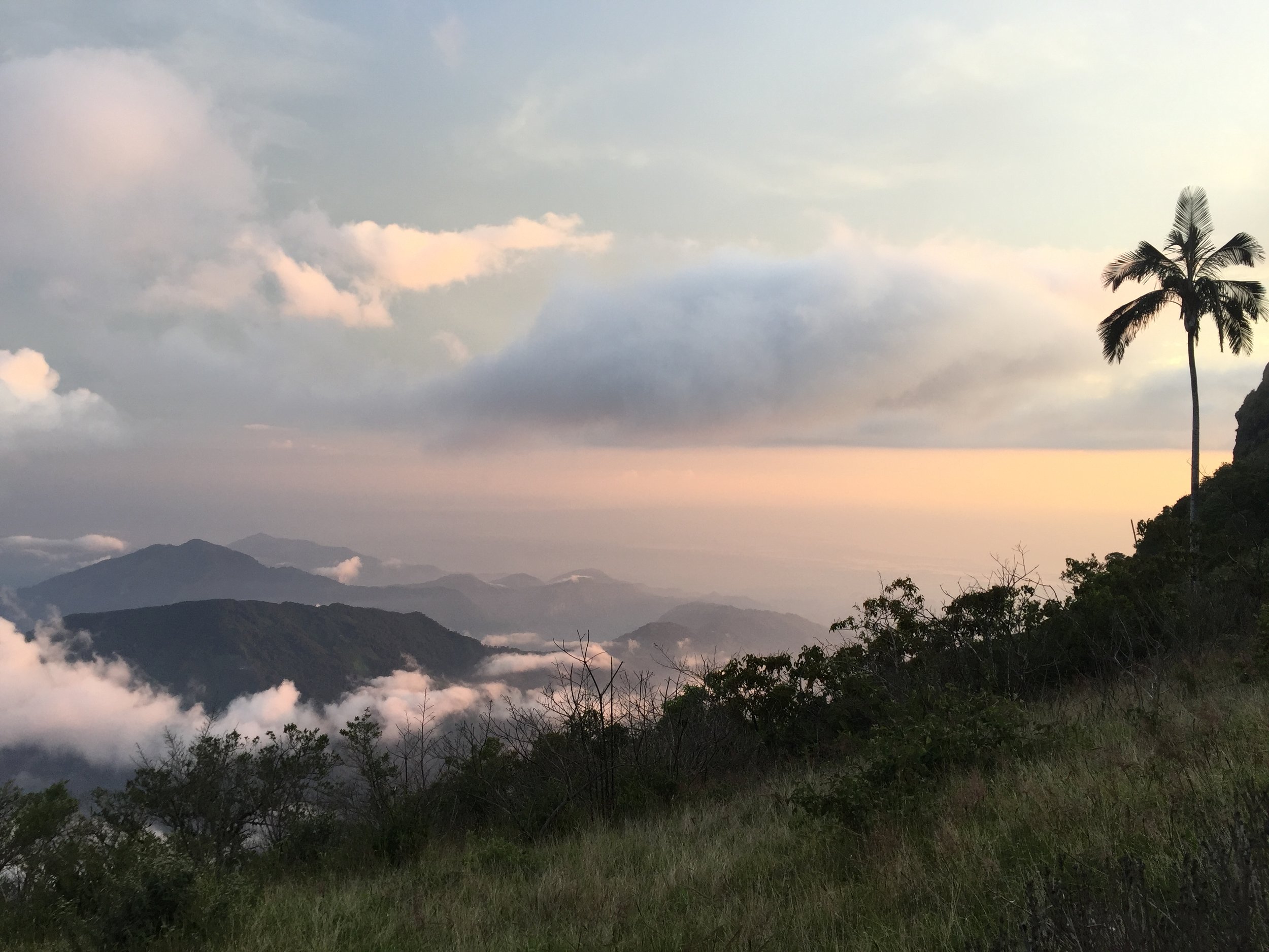 CERRO KENNEDY, COLOMBIA – JULY 28TH, 2017: The view from the summit of Cerro Kennedy, 7000 feet above the town of Minca. Clouds stream down from the lower peaks to the sea, less than 41 miles away.