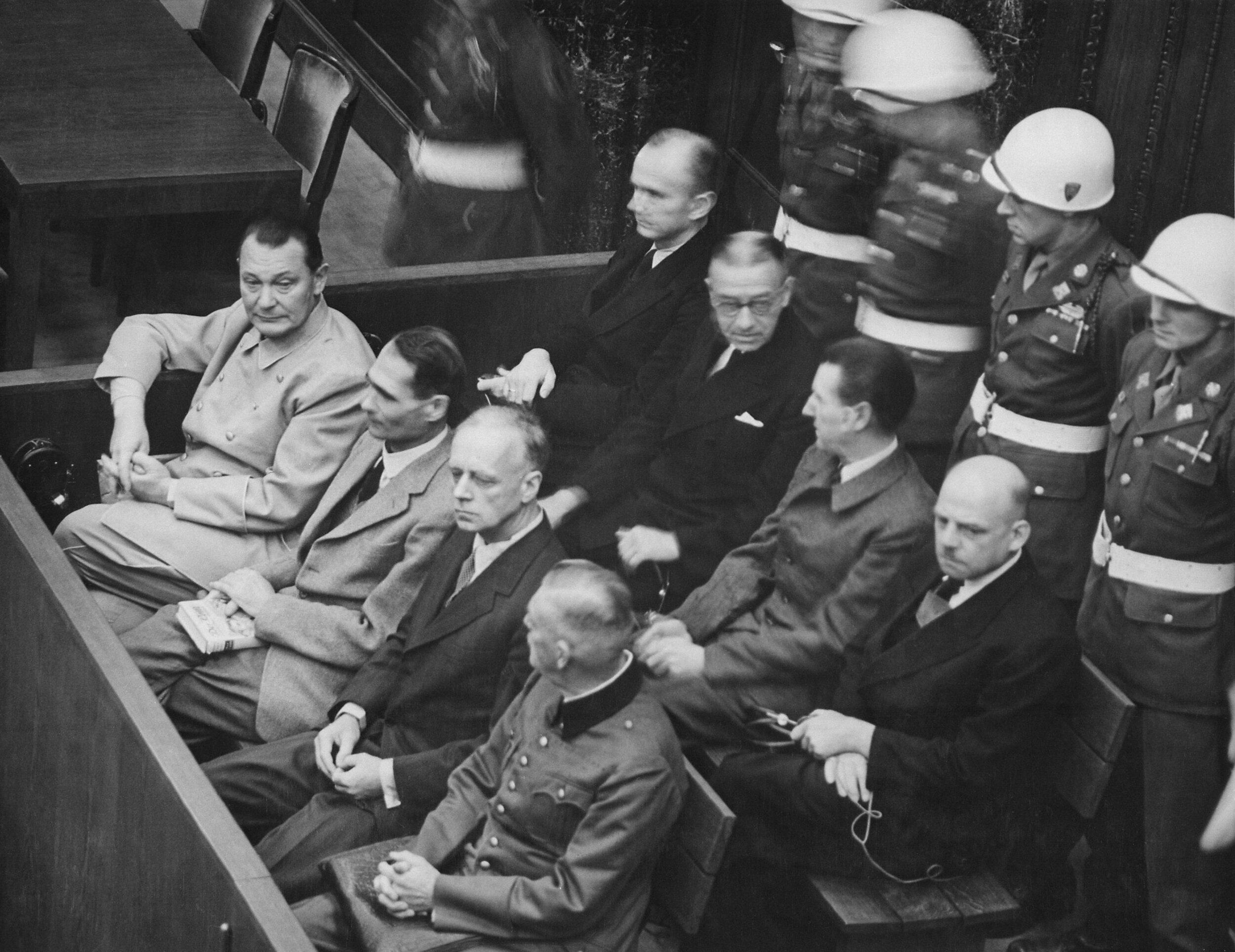 PICTURED: Nuremberg Trials. Defendants in their dock, circa 1945-1946. (in front row, from left to right): Hermann Göring, Rudolf Heß, Joachim von Ribbentrop, Wilhelm Keitel (in second row, from left to right): Karl Dönitz, Erich Raeder, Baldur von …