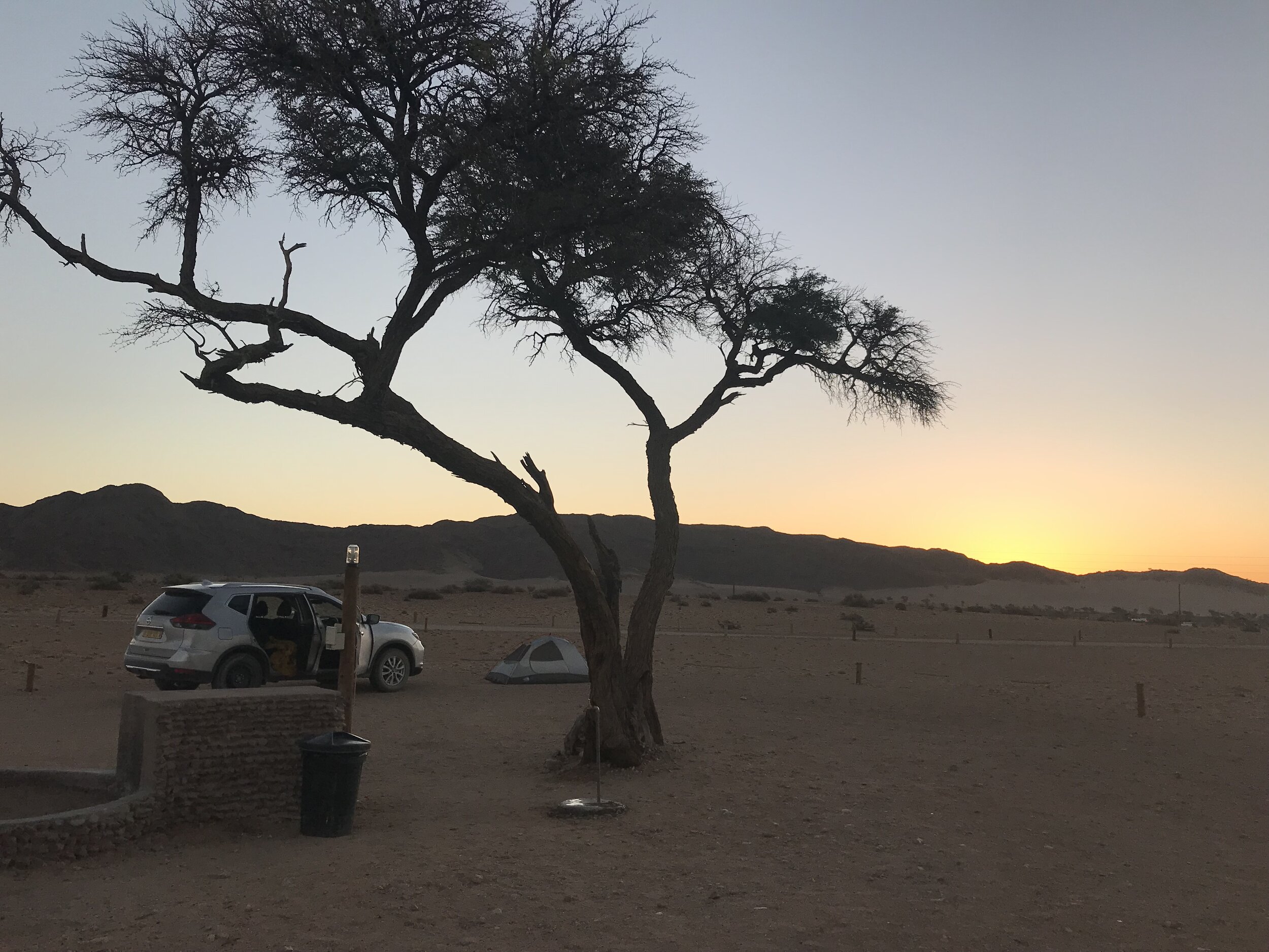 PICTURED: The view of the sun setting behind the dunes from my camp at the “primitive” option at Sossusvlei rest camp.