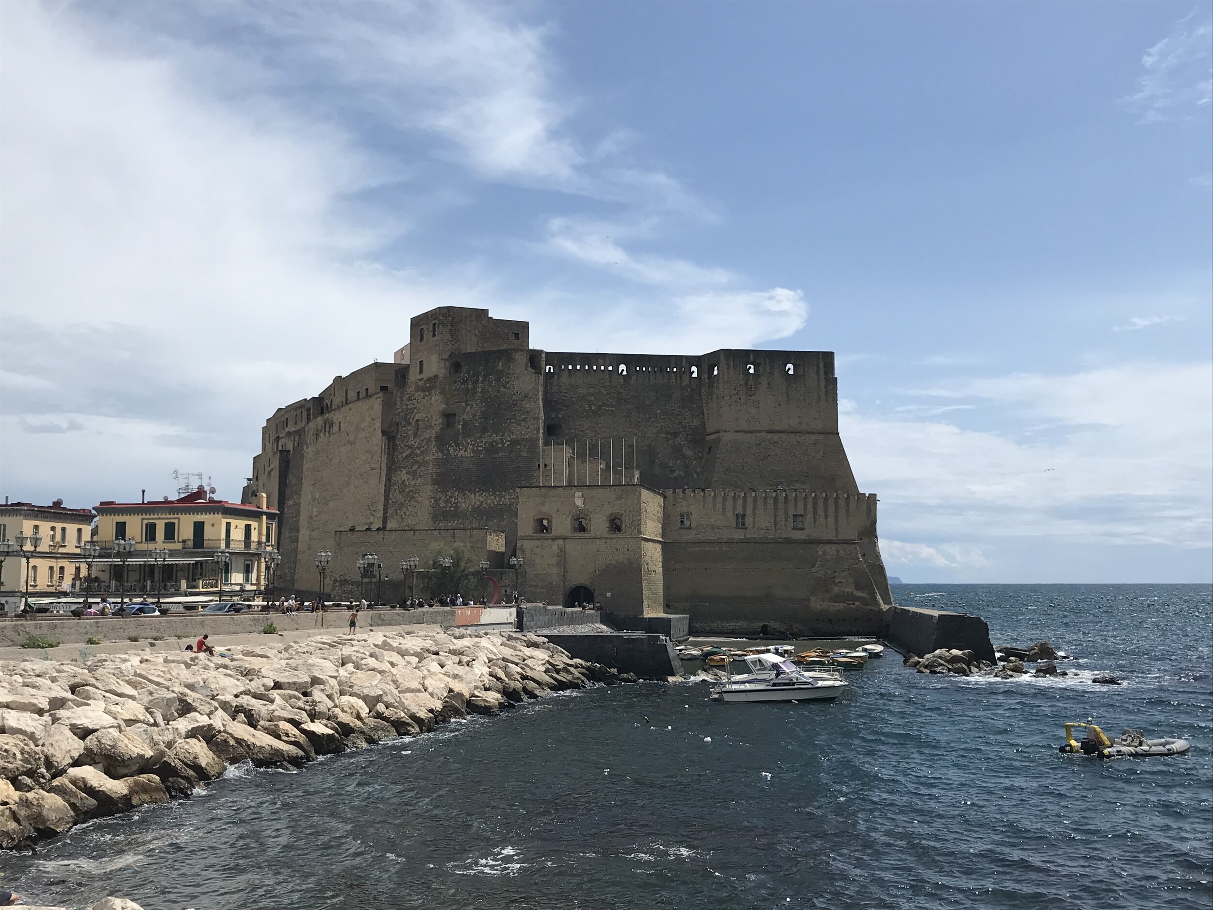   NAPLES, Italy. August 7th, 2020. PICTURED:  The tan colors of Castel dell’Ovo, glitter on the rocks at the edge of the sea on Naples’ Lungo Mare street. 