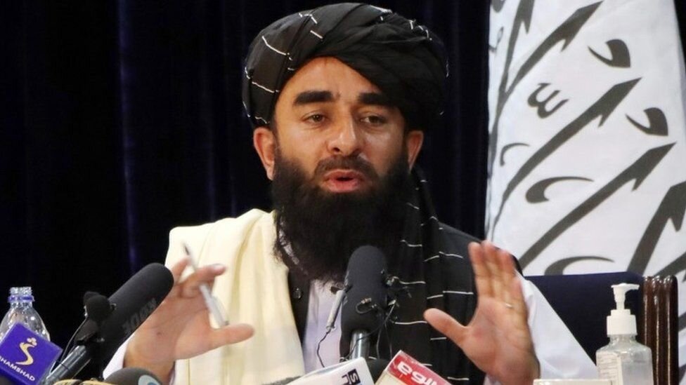 PICTURED: Taliban official spokesman, Zabihullah Mujahid gives a press conference in Kabul. PC: Reuters. Fair Use.