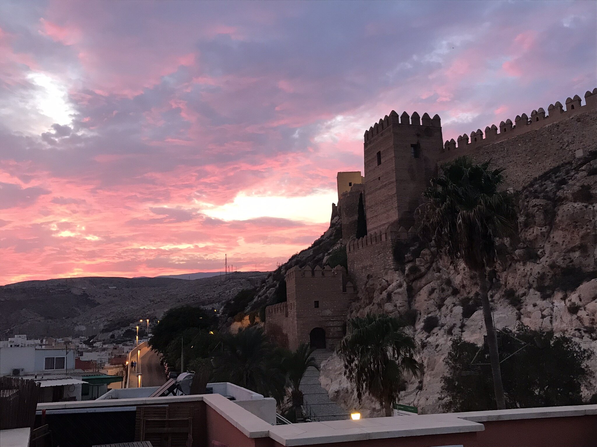 ALMERIA, Spain. October 1st, 2021. PICTURED: The sun goes down behind the Alcazabar of Almeria, seen from the roof of a local Moroccan eatery. Photo credit: Andy Corbley ©.