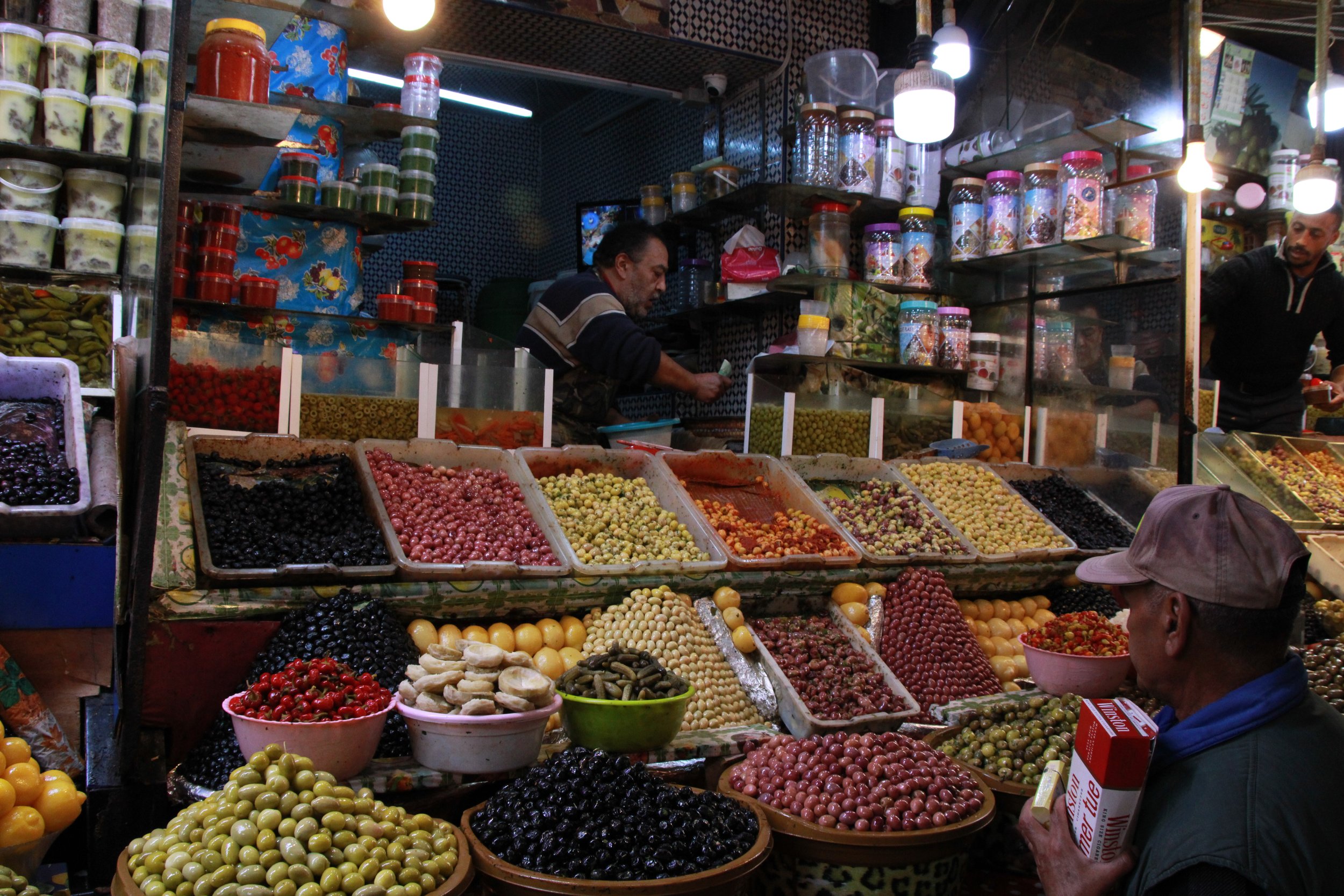  PICTURED: A vendor in the fruits, nuts, and spice souk, fulfills an order amid the sour smell of vinegar and olives, the smells of spices, and of freshly baked sweeties. PC: Andrew Corbley © 