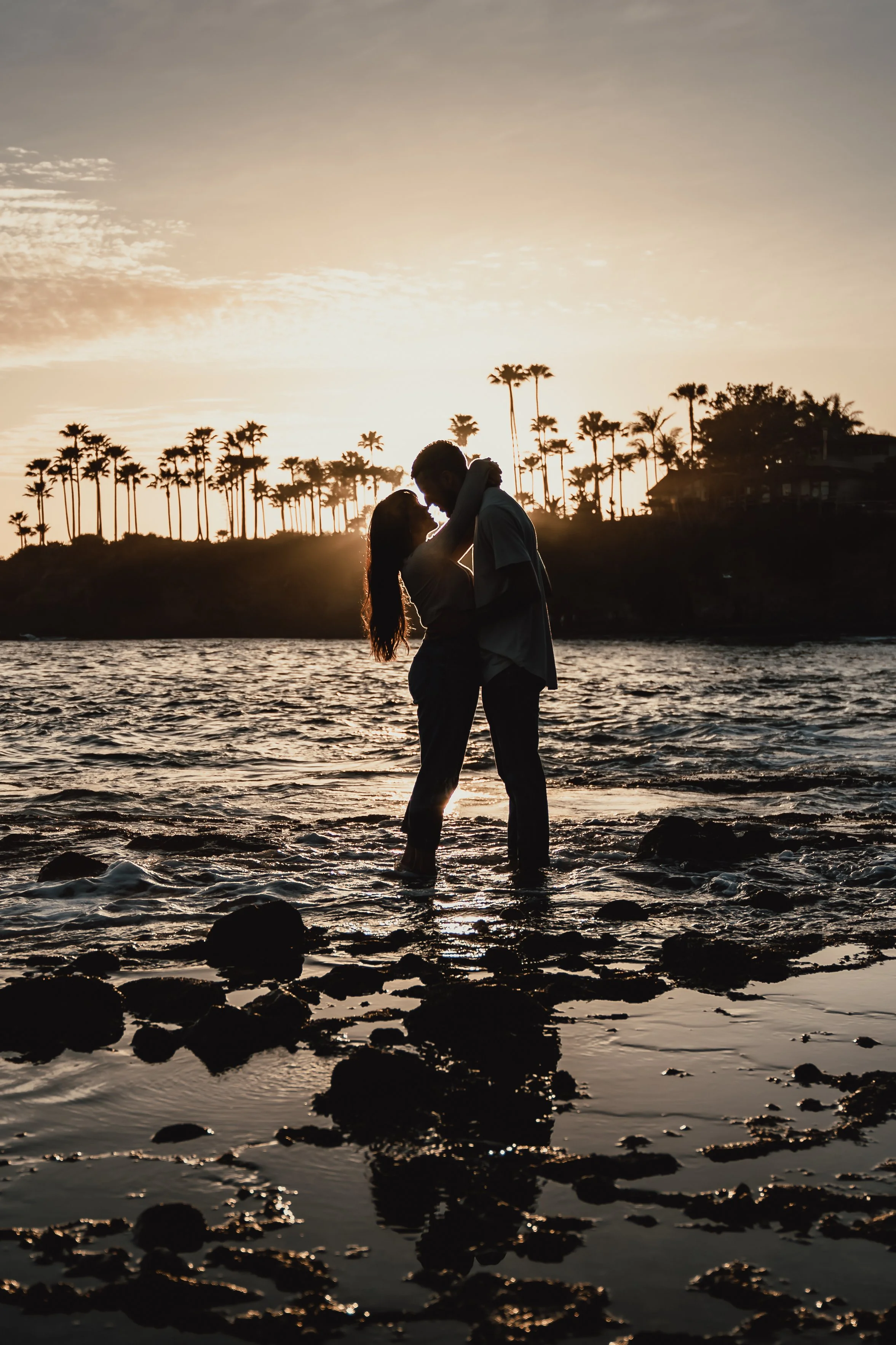 Couple silhouette portrait on the rocky shoreline at Laguna Beach during sunset.