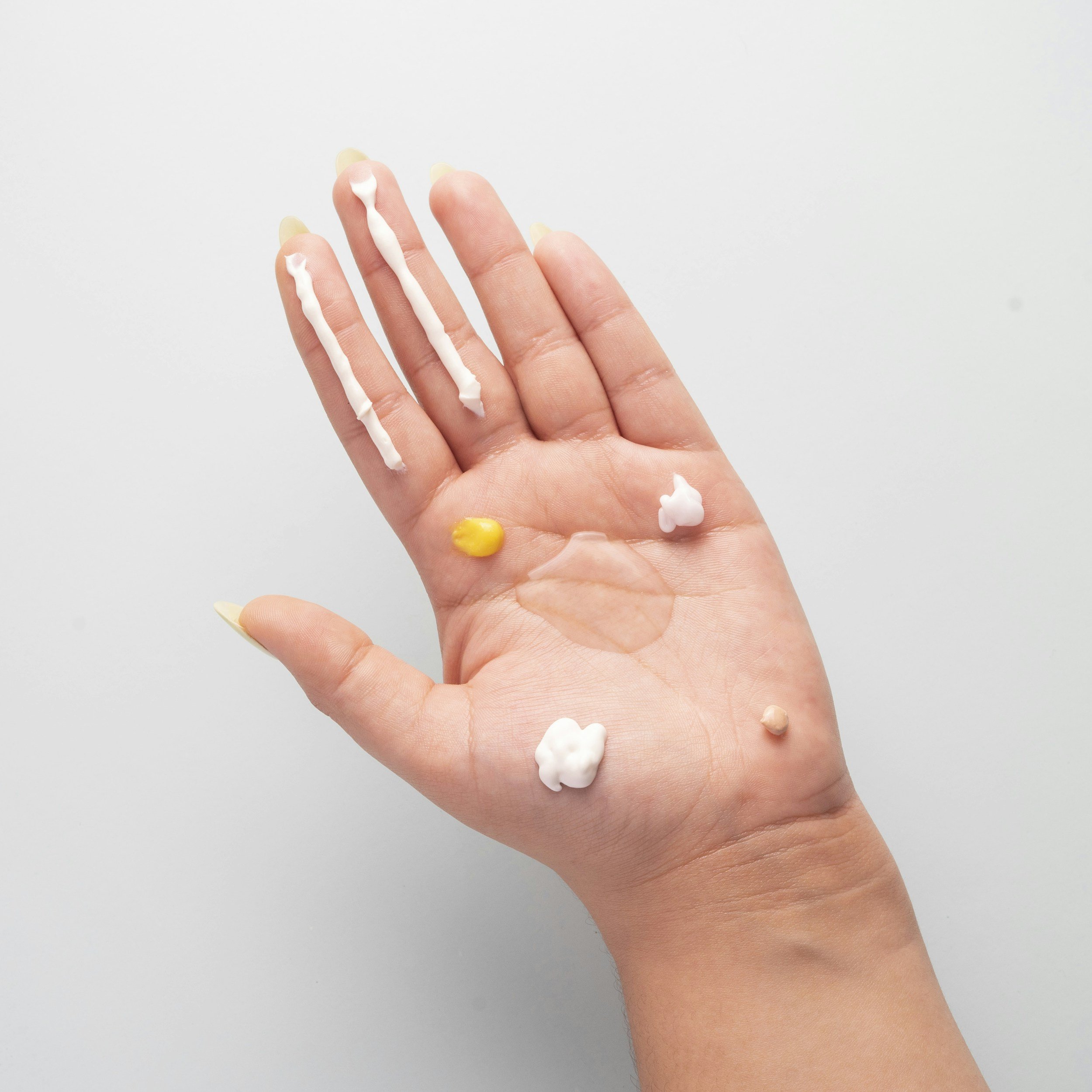 a woman's hand with lots of different blobs of skincare creams on her