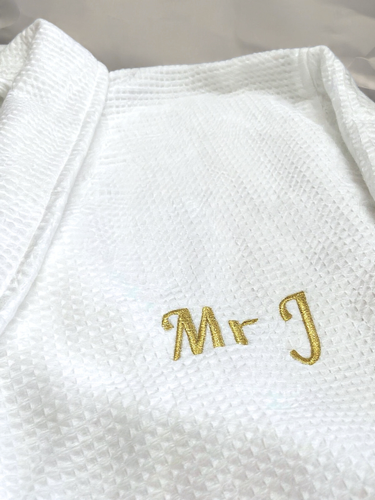White textured martial arts gi with embroidered gold 'Mr J' on the chest.
