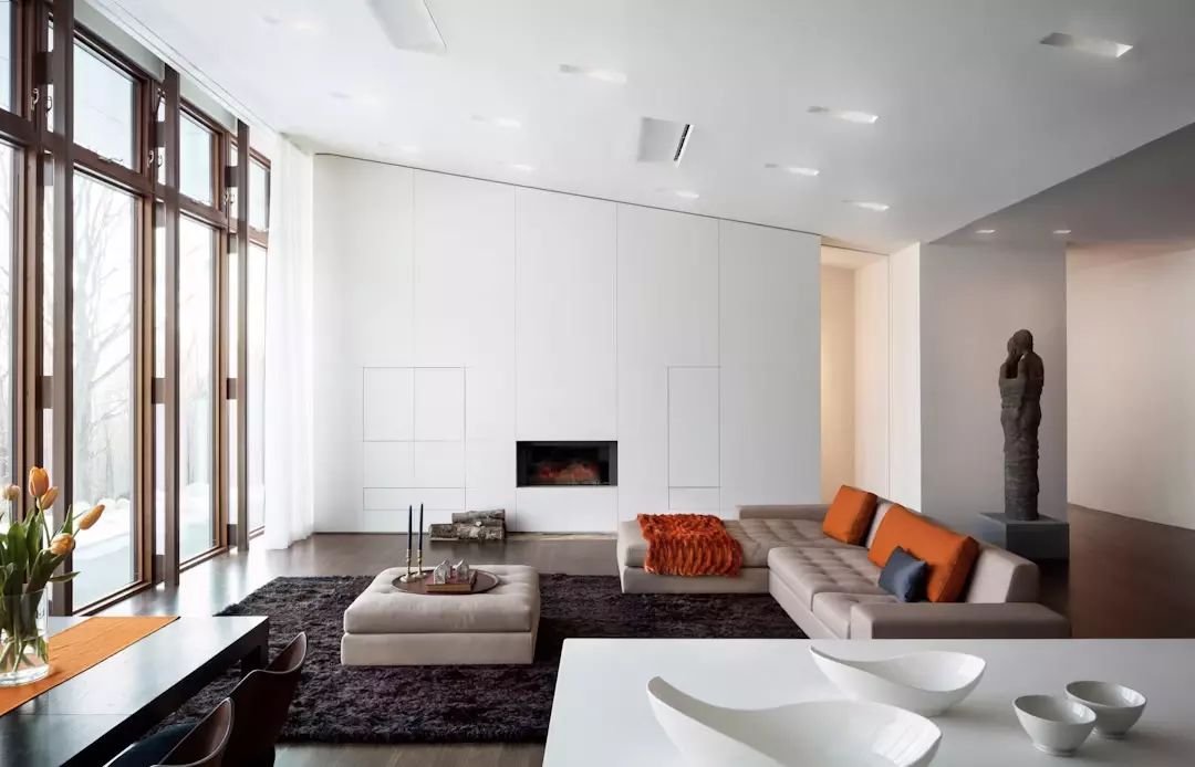 Floor-to-ceiling custom millwork creates a sleek, flush fireplace surround, integrating storage with minimalist design. The seamless white panels blend into the architecture, adding modern sophistication to the living space.