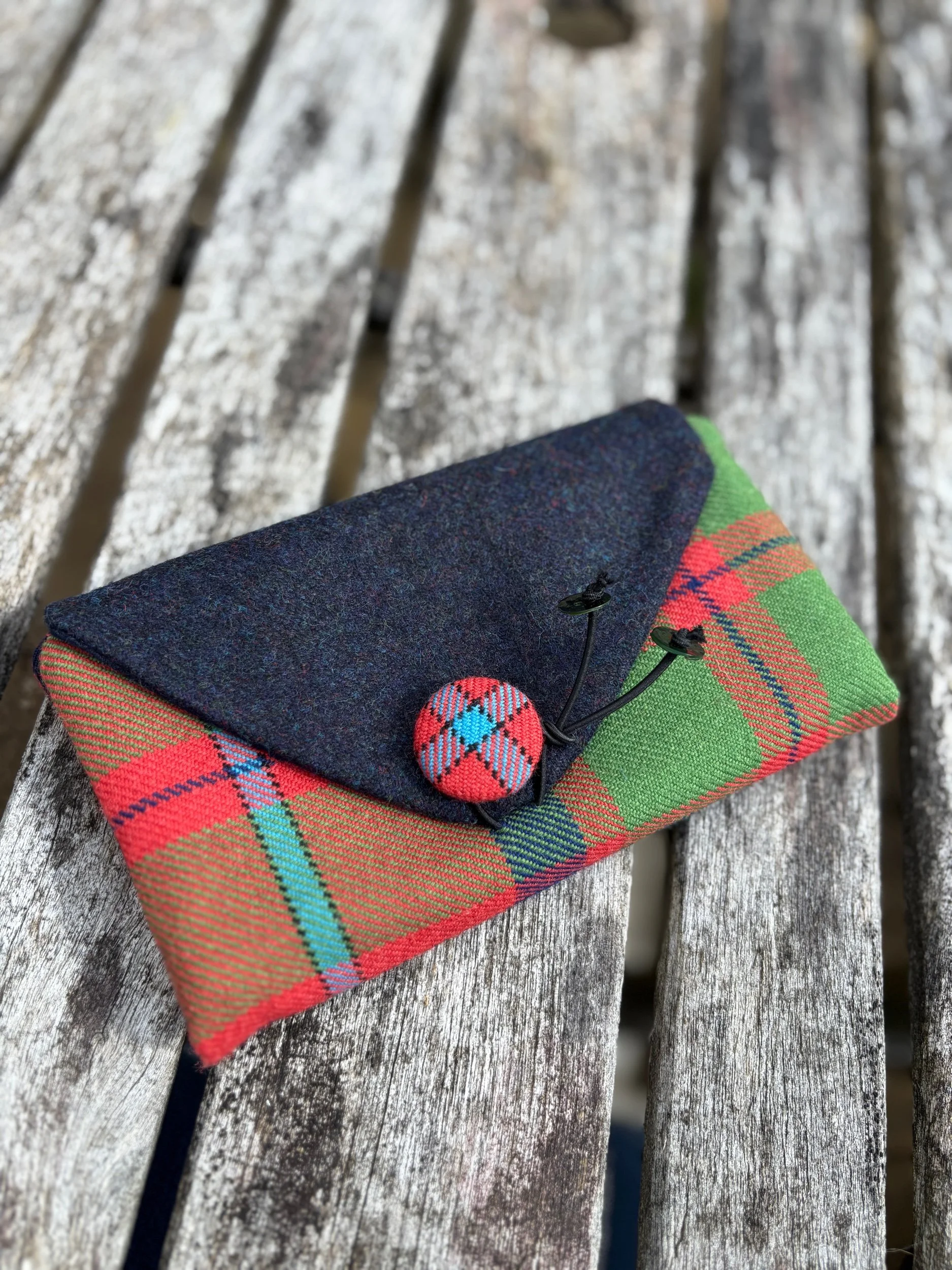 Front view of handmade Scottish tartan clutch bag in Shaw of Tordarroch with dark blue tweed flap and hand‑covered button
