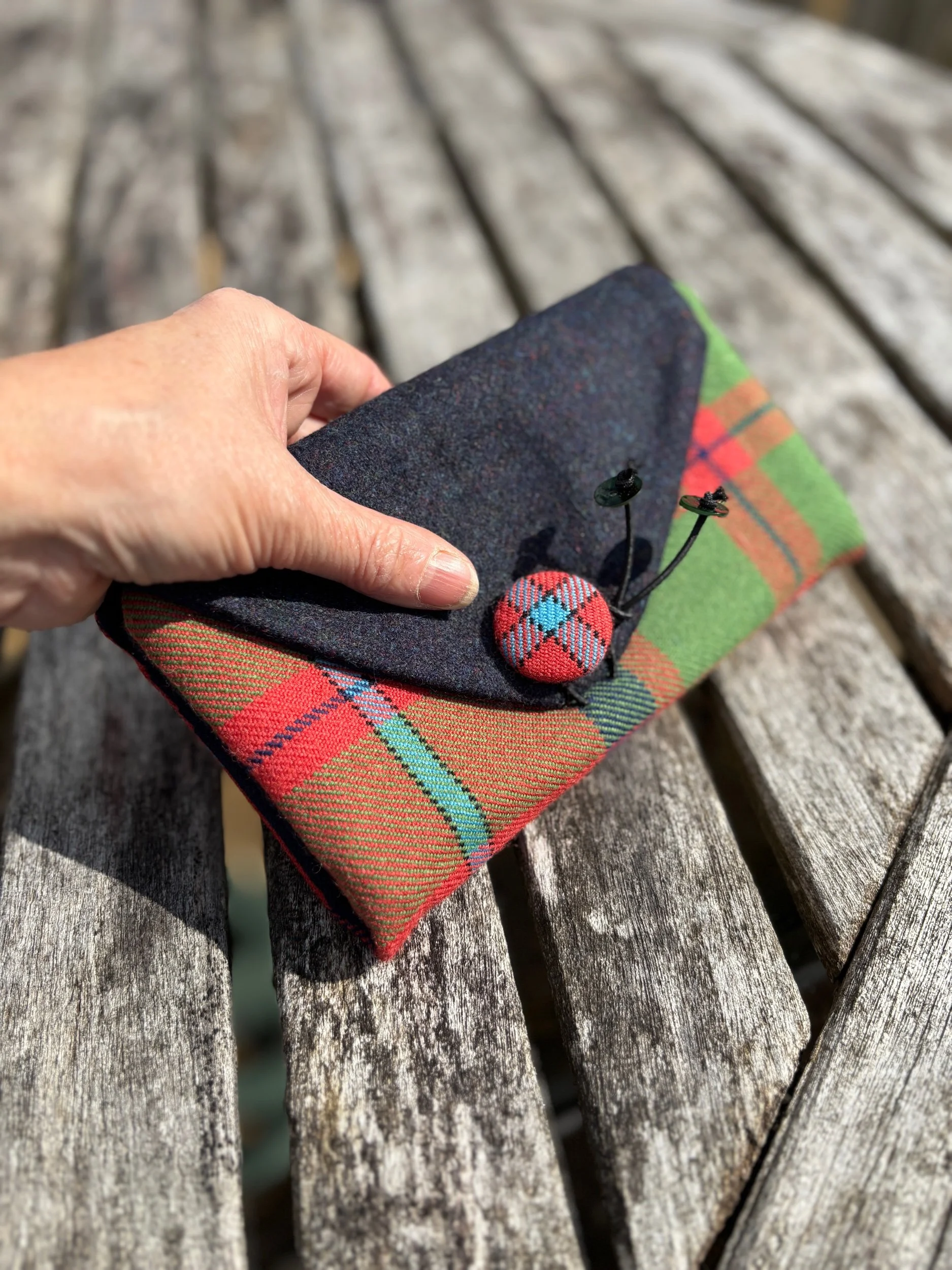 Hand holding the Scottish tartan clutch bag to show size and scale of the purse