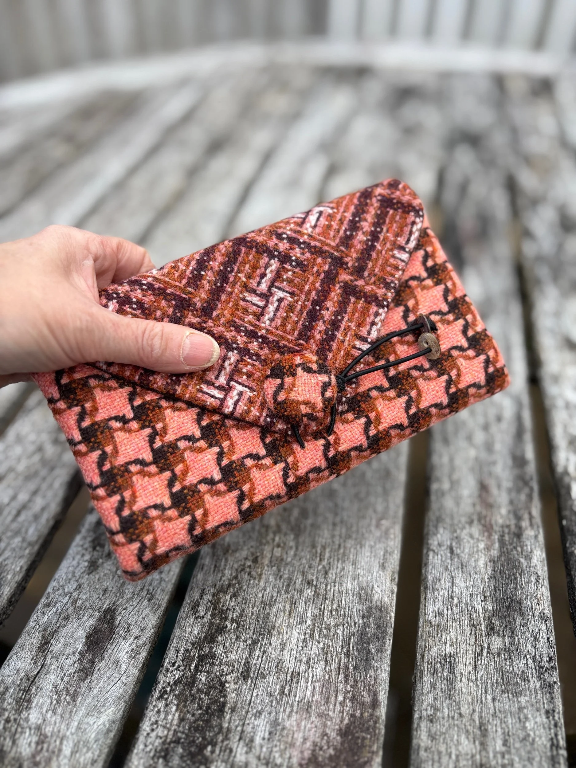 Handheld view of peach contemporary tweed clutch bag showing scale and size when carried