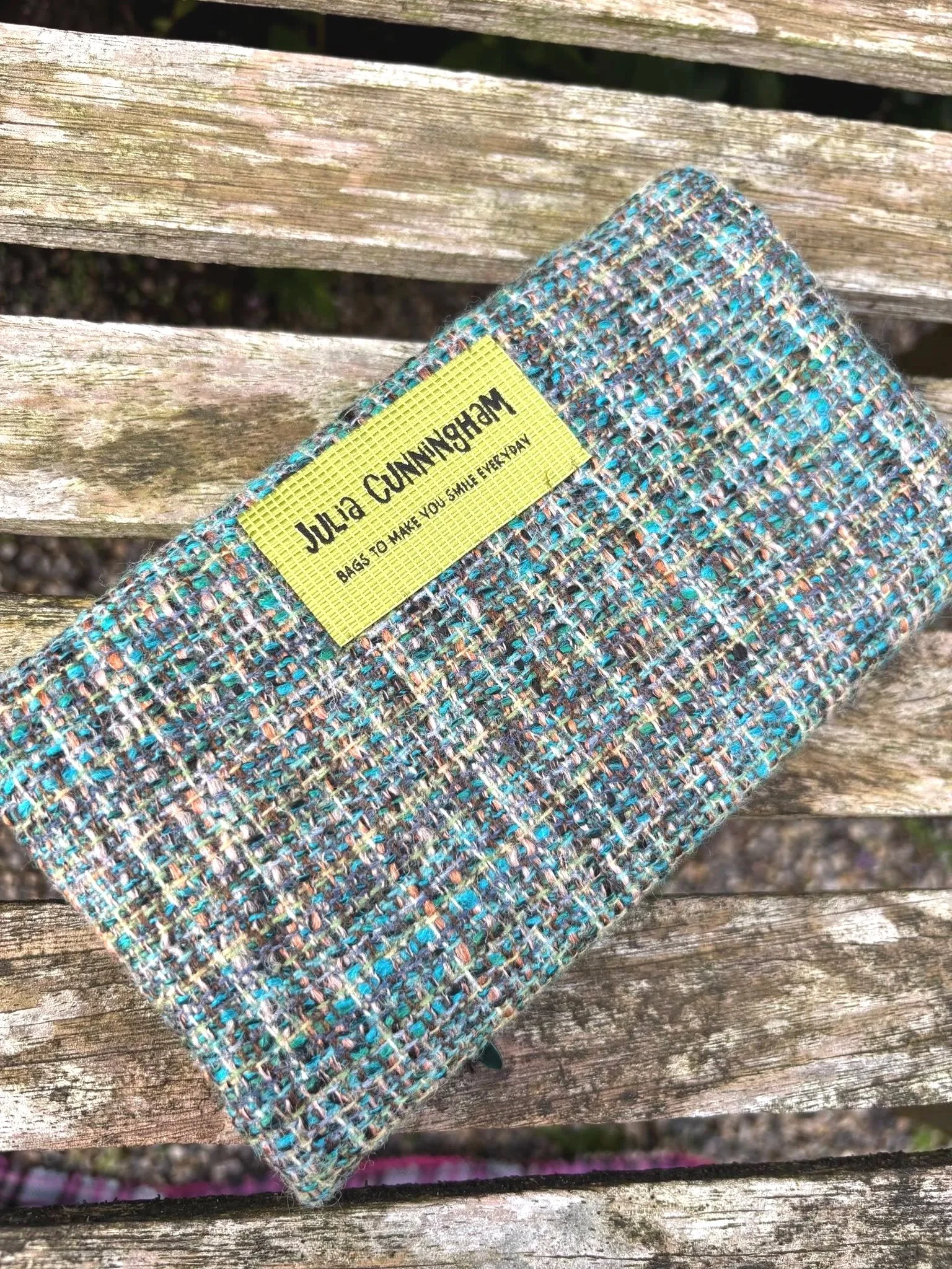Back image of handmade Scottish clutch purse showing fabric texture and brand label detail by Julia Cunningham