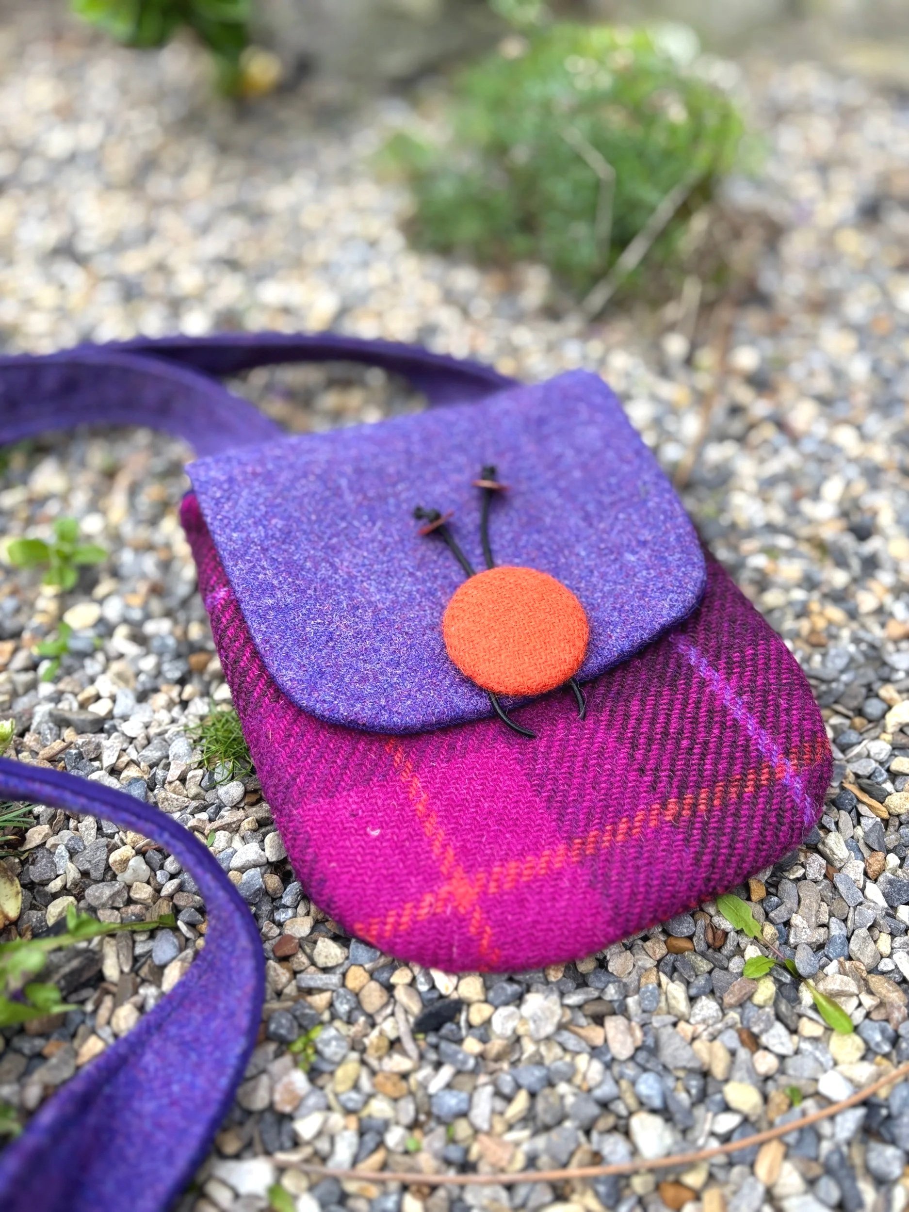 Close up of Handmade purple and orange Harris tweed crossbody phone bag with purple flap closure, crafted in Scotland by Julia Cunningham