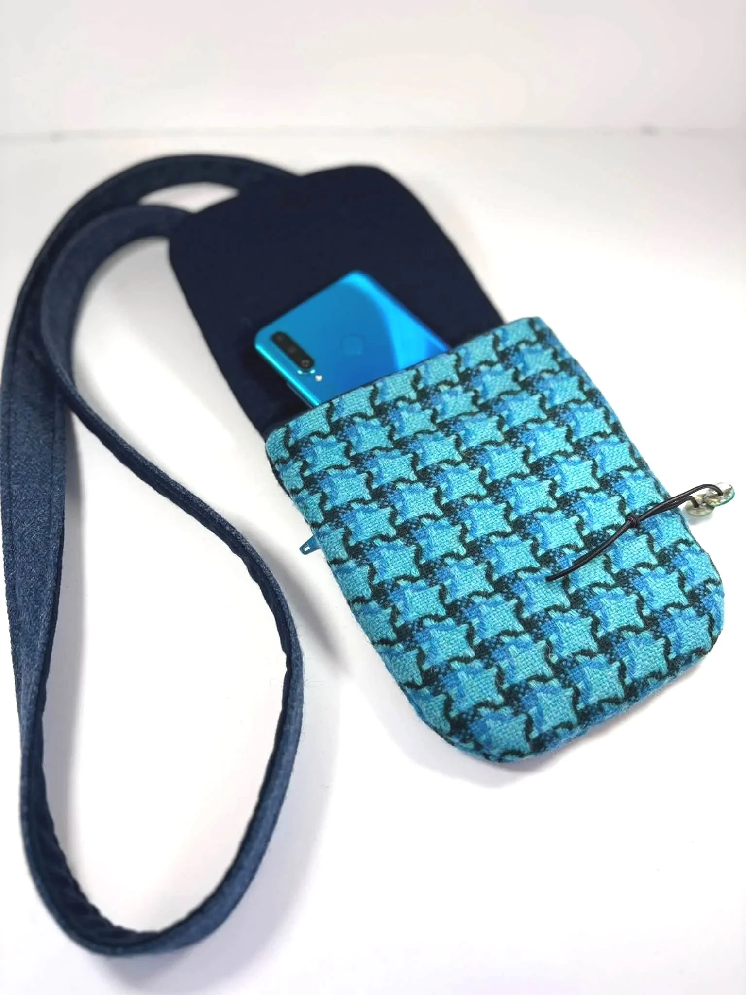 inside of a cross body phone bag in blue tweed being used with a phone