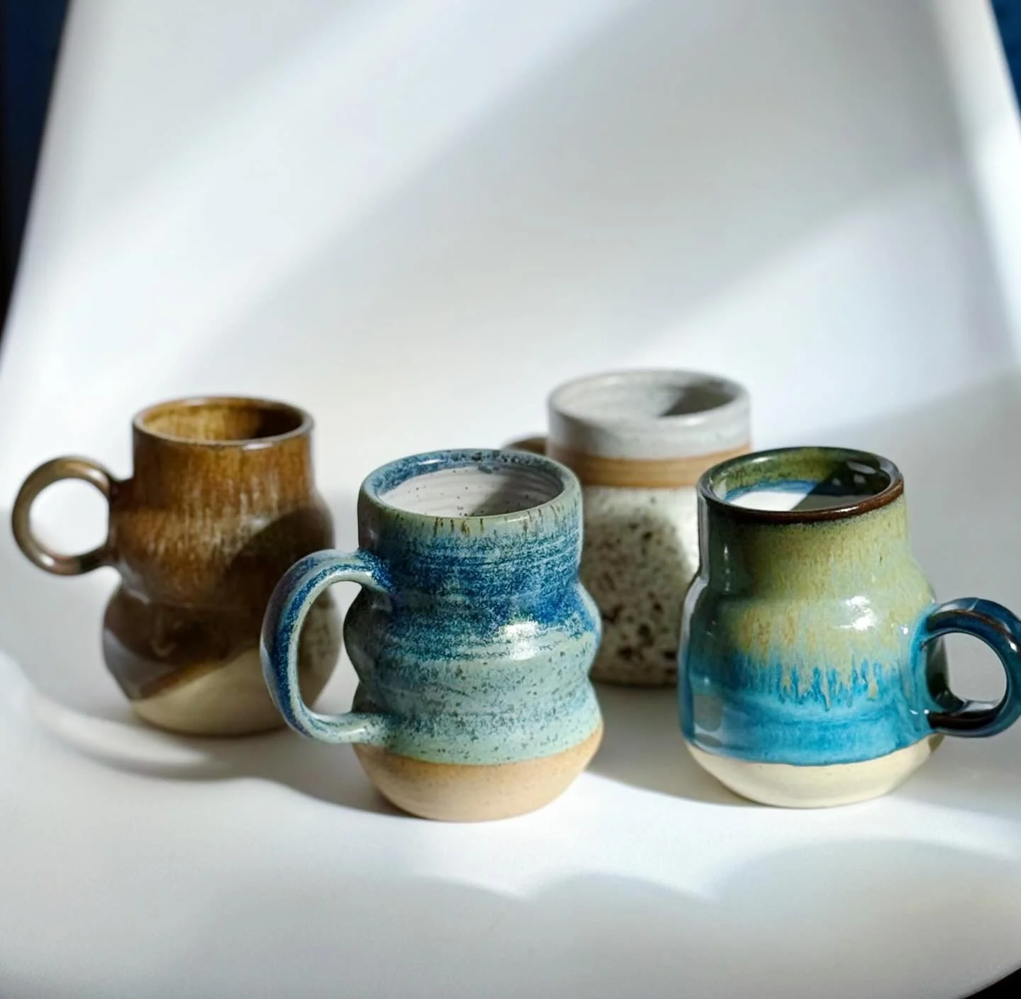 A few funky mug shapes and some glazes I&rsquo;ve been playing with (displayed on my super fancy chair backdrop 👍🏼)