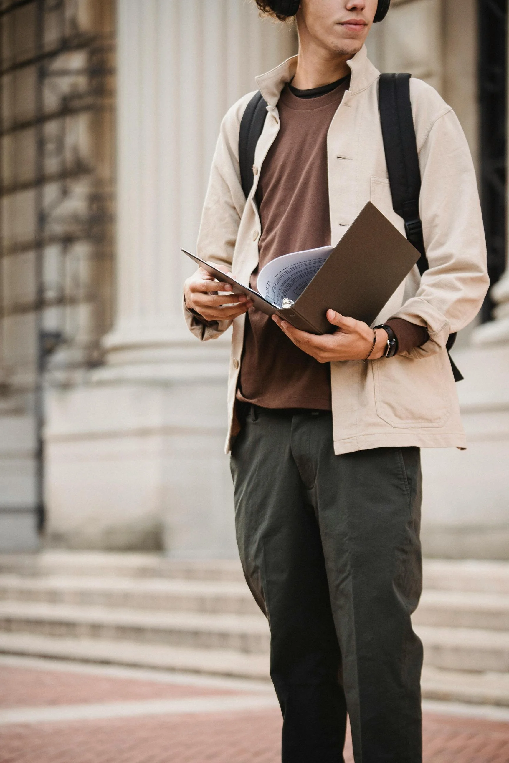 student outside high school with binder and notebook