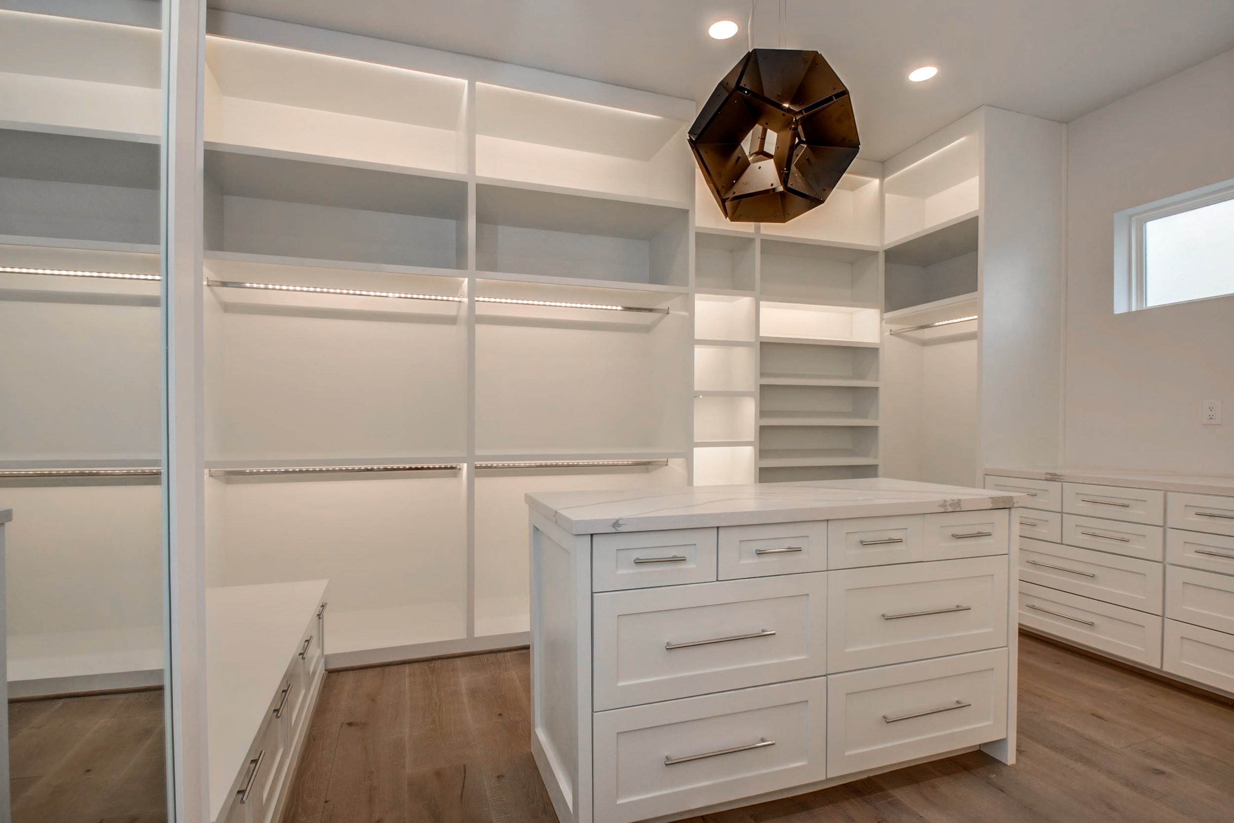 Walk in closet with an island and chandelier