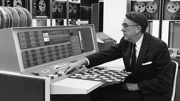 Arthur Samuels, who coined the phrase “machine learning,” works with an early IBM machine and a checkerboard.