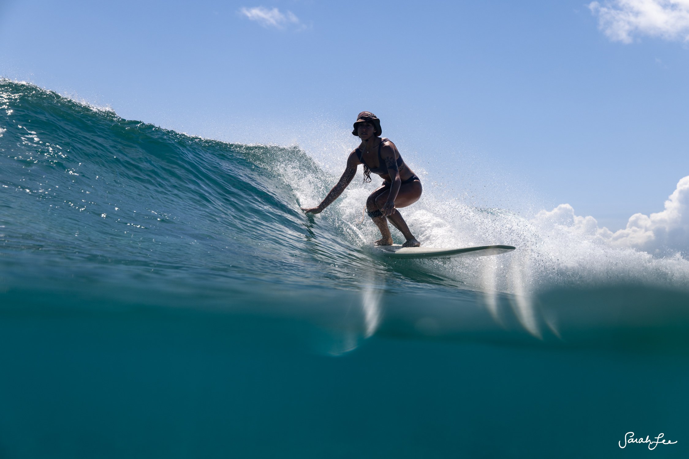 Female longboarder in the tropics with a surf hat