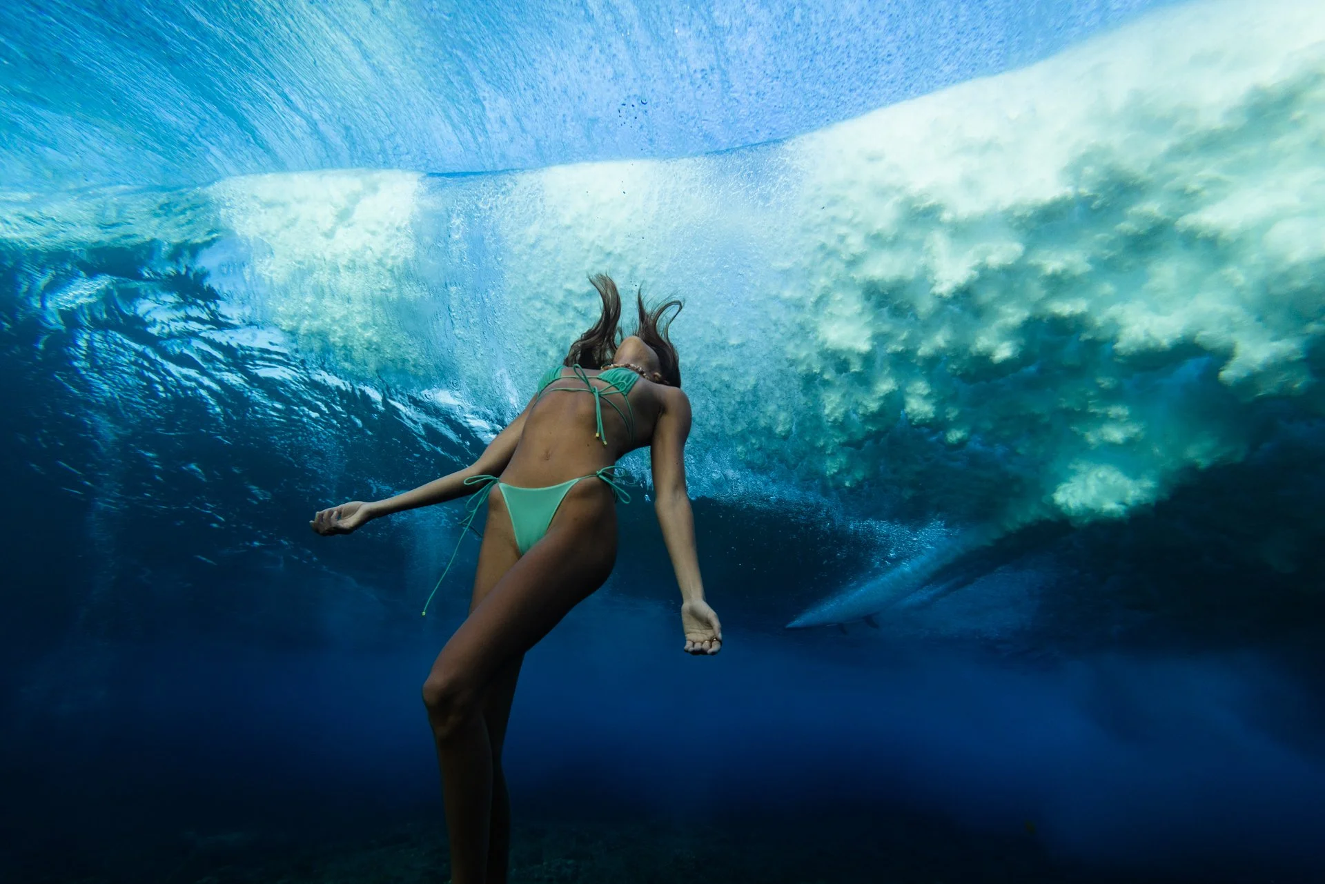 Elena Aoki, underwater model swimming beneath Cloudbreak in Fiji.