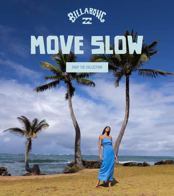 A woman standing on a grassy area near the beach, with two palm trees in the background under a partly cloudy sky, advertising Billabong's 'Move Slow' collection.