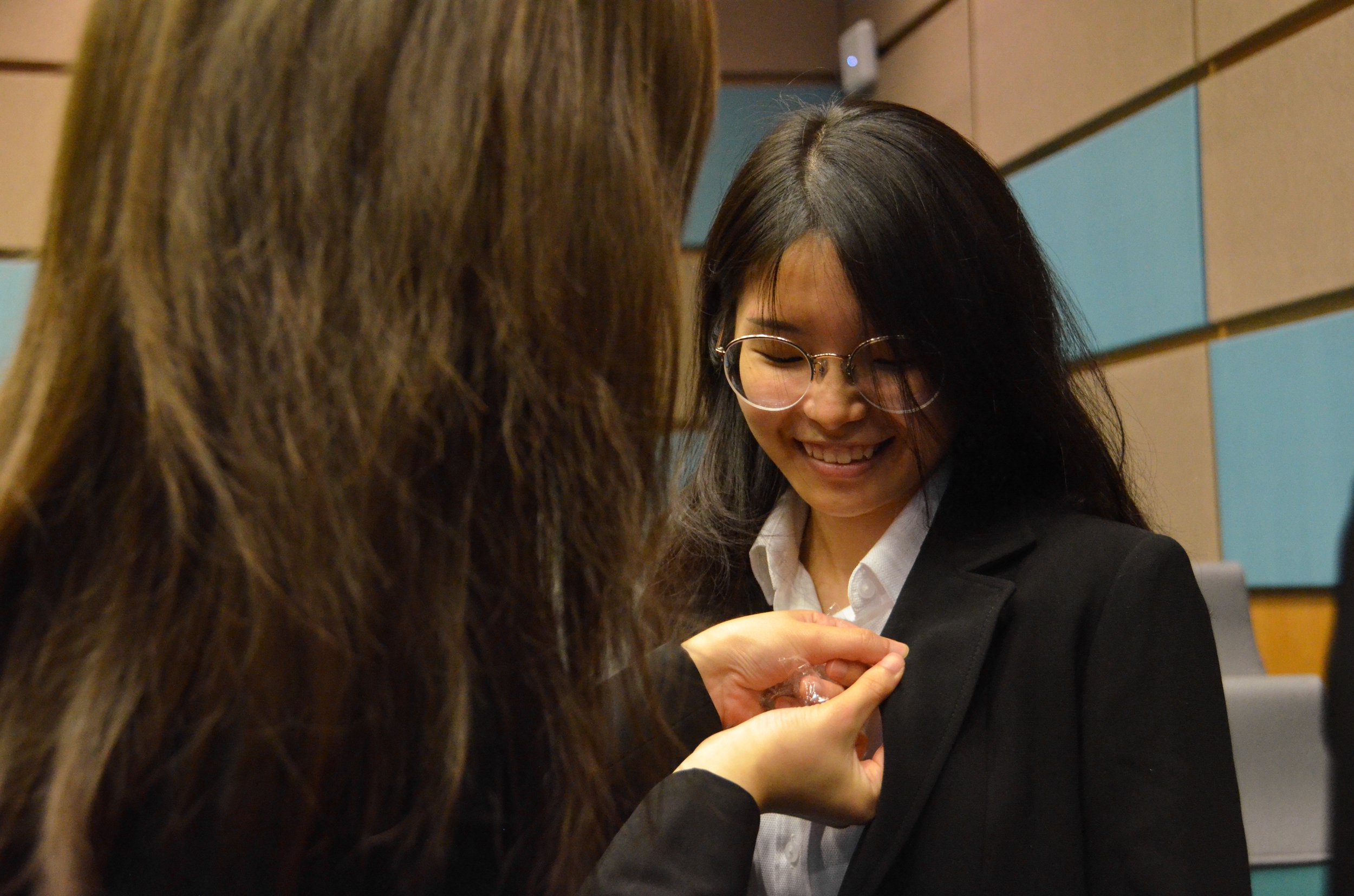 An OGL pinning the NUS Law badge on her freshman