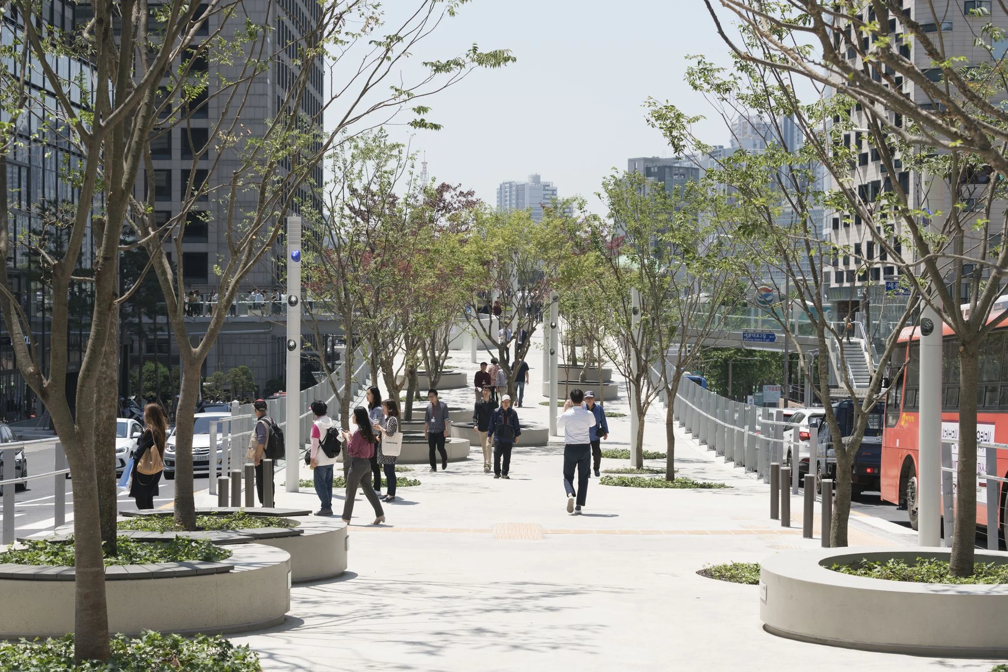 Located in the heart of Seoul, a true plant village has been realised on a former inner city highway in an ever-changing urban area accommodating the biggest variety of Korean plant species and transforming it into a public 983-metre long park gathering 50 families of plants including trees, shrubs and flowers displayed in 645 tree pots, collecting around 228 species and sub-species. In total, the park will include 24,000 plants (trees, shrubs and flowers) that are newly planted many of which will grow to their final heights in the next decade. Seoullo , the Korean name for Skygarden translates to ‘towards Seoul’ and ‘Seoul Street’, while 7017 marks the overpass’ construction year of 1970, and its new function as a public walkway in 2017. The pedestrianised viaduct next to Seoul's main station is the next step towards making the city and especially the central station district, greener, friendlier and more attractive, whilst connecting all patches of green in the wider area. In central Seoul, a true plant village has been realised on a former inner city highway in an ever-changing urban area accommodating the biggest variety of Korean plant species and transforming it into a public 983-metre long park gathering 50 families of plants including trees, shrubs and flowers displayed in 645 tree pots, collecting around 228 species and sub-species. In total, the park will include 24,000 plants (trees, shrubs and flowers) that are newly planted many of which will grow to their final heights in the next decade. Since the project was won by MVRDV in May 2015, the main challenge of the Skygarden has been to transform the existing overpass into a public garden, overlaying a matrix of Korean flora onto the 16m elevated steel and concrete structure. How to transform a 1970’s highway into a Skygarden and how to change the daily life of thousands of people who cross Seoul’s city centre every day? From the start, MVRDV engaged with this need to change the forgotten and existing infrastructure into a green symbol that will become a catalyst for a greener quarter for Seoul. Together with the municipality, local NGO’s, landscape teams and city advisers are committed to accommodating the biggest diversity of flora into a strictly urban condition. New bridges and stairs connect the viaduct with hotels, shops and gardens. Photos by Ossip van Duivenbode
