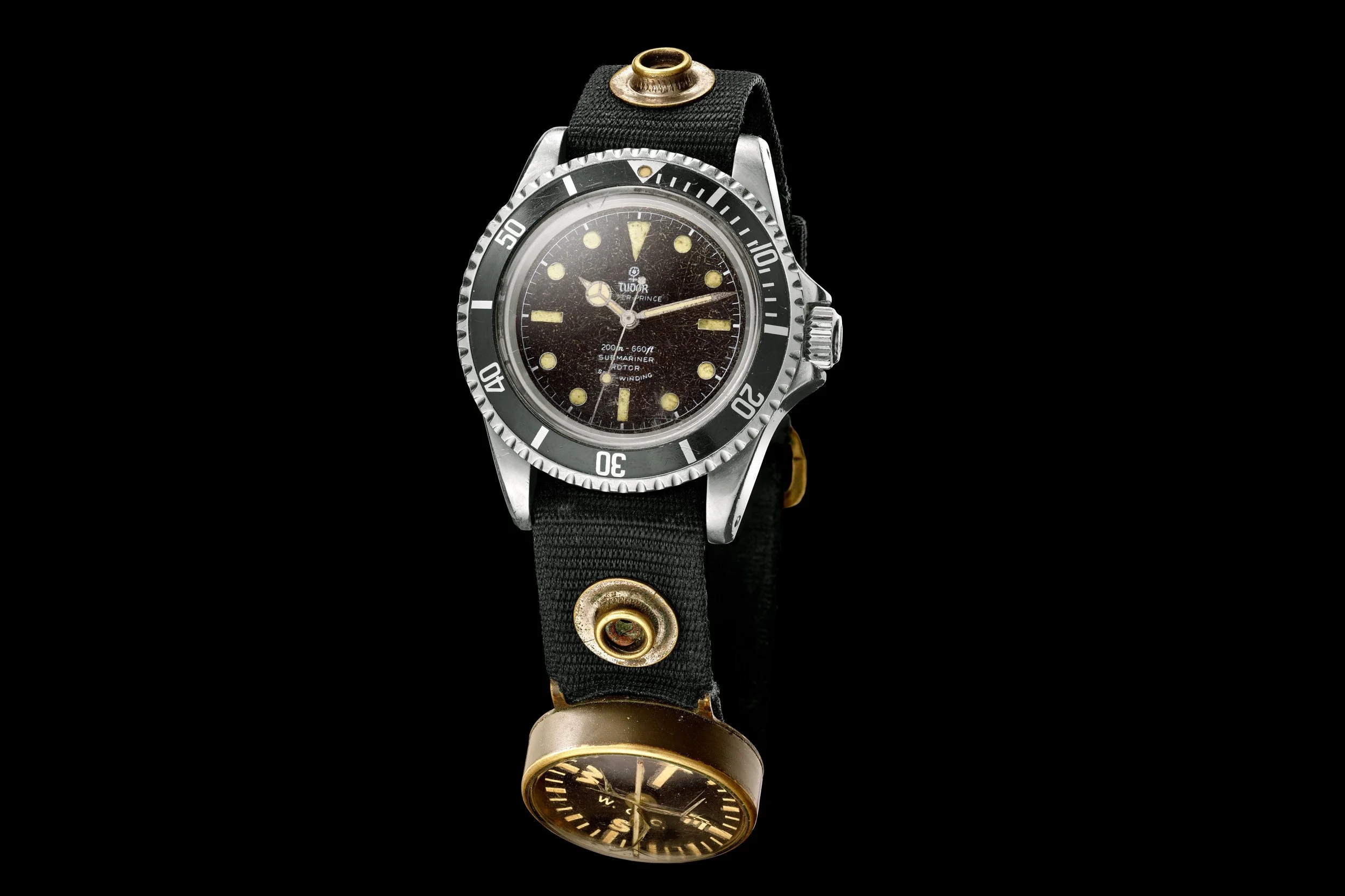 Philip "Moki" Martin's Navy-issued 1964 Tudor Oyster Prince Submariner ref. 7928 on a nylon strap with a wrist compass, on display at the Navy SEAL Museum San Diego
