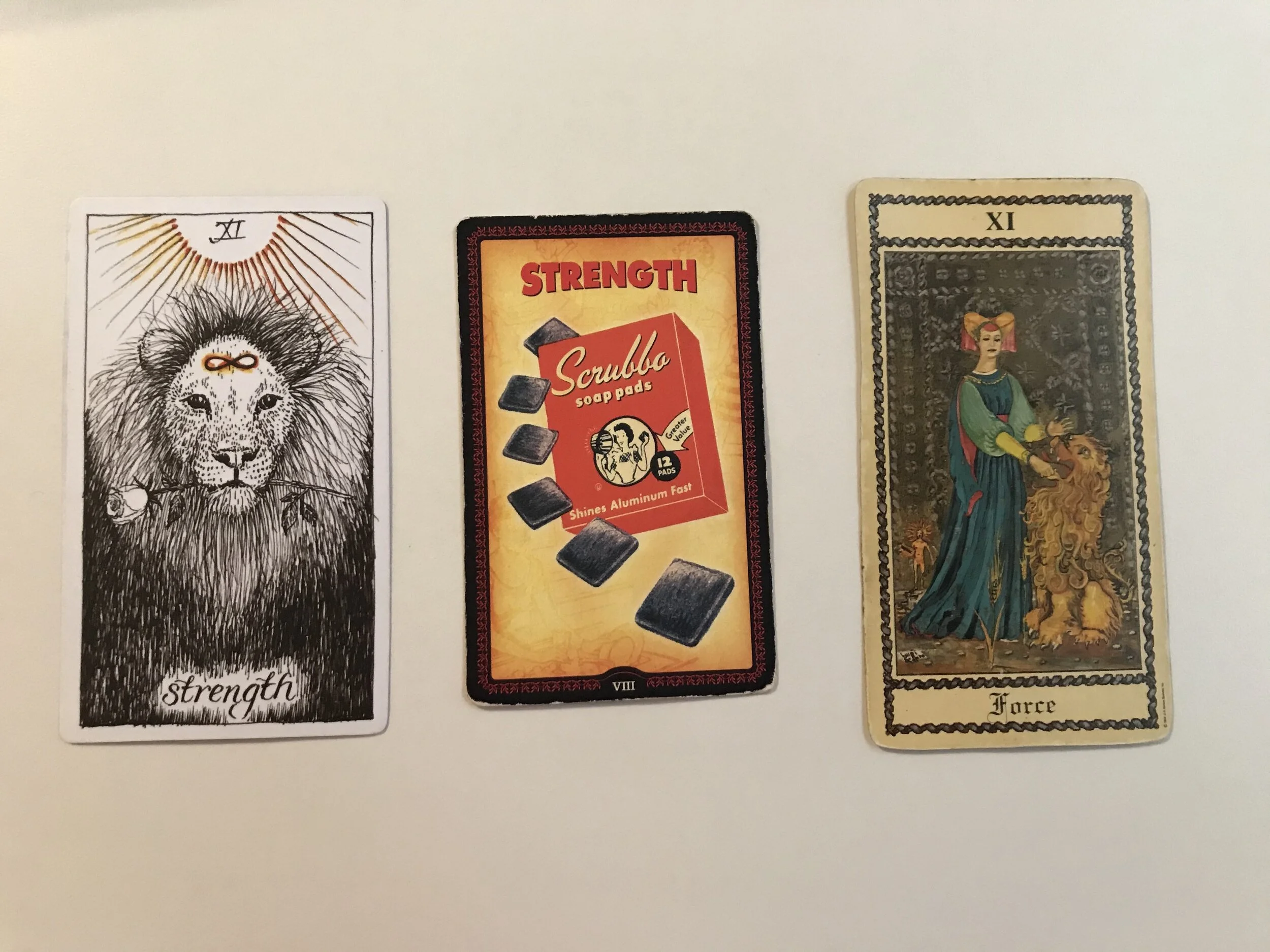 The Strength card from left to right: The Wild Unknown Tarot, The Housewives’ Tarot, The Medieval Scapini Tarot