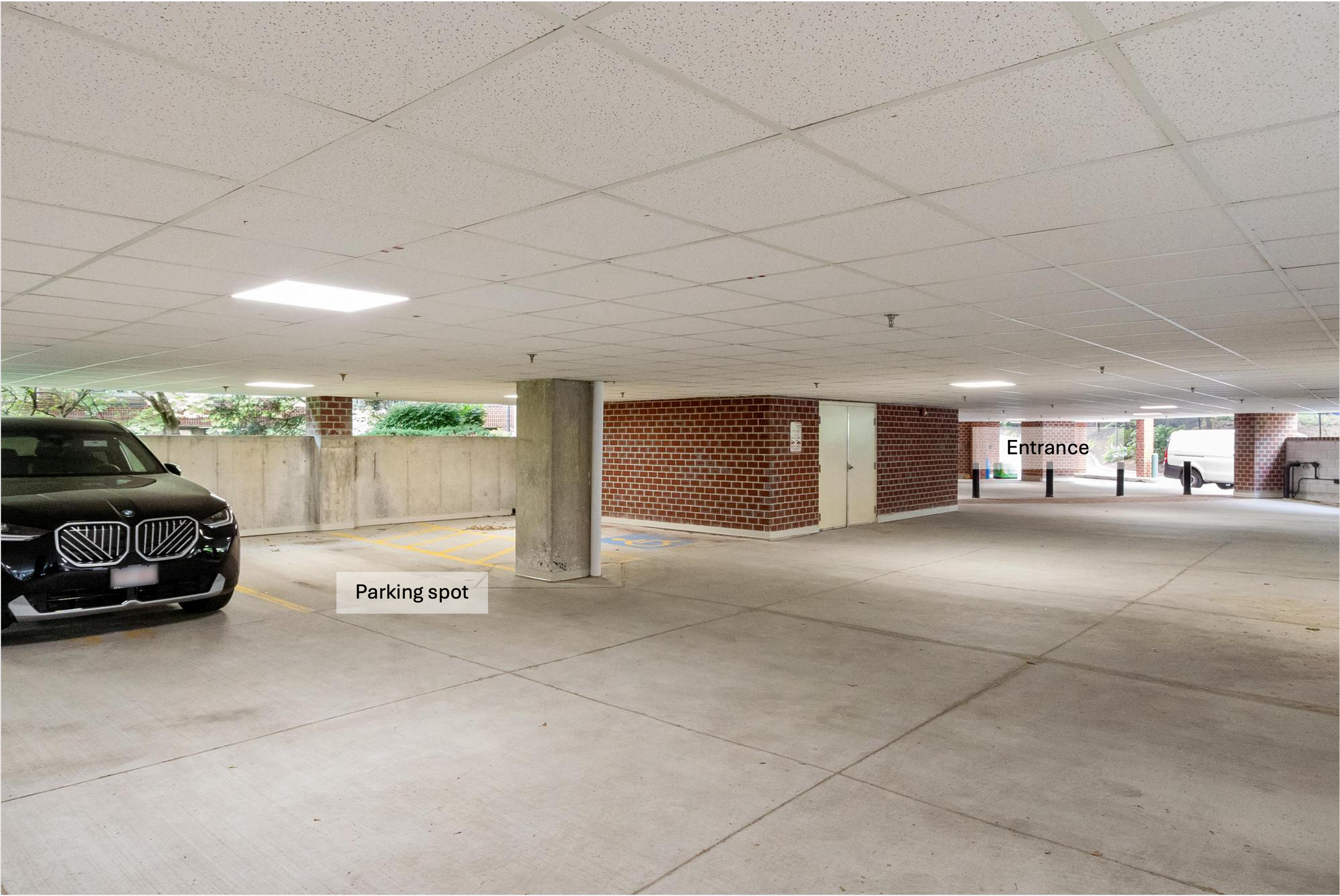 Underground parking garage with a black car on the left, concrete floor, brick walls on the right, and ceiling with ventilation. Markings indicate a parking spot and an entrance.