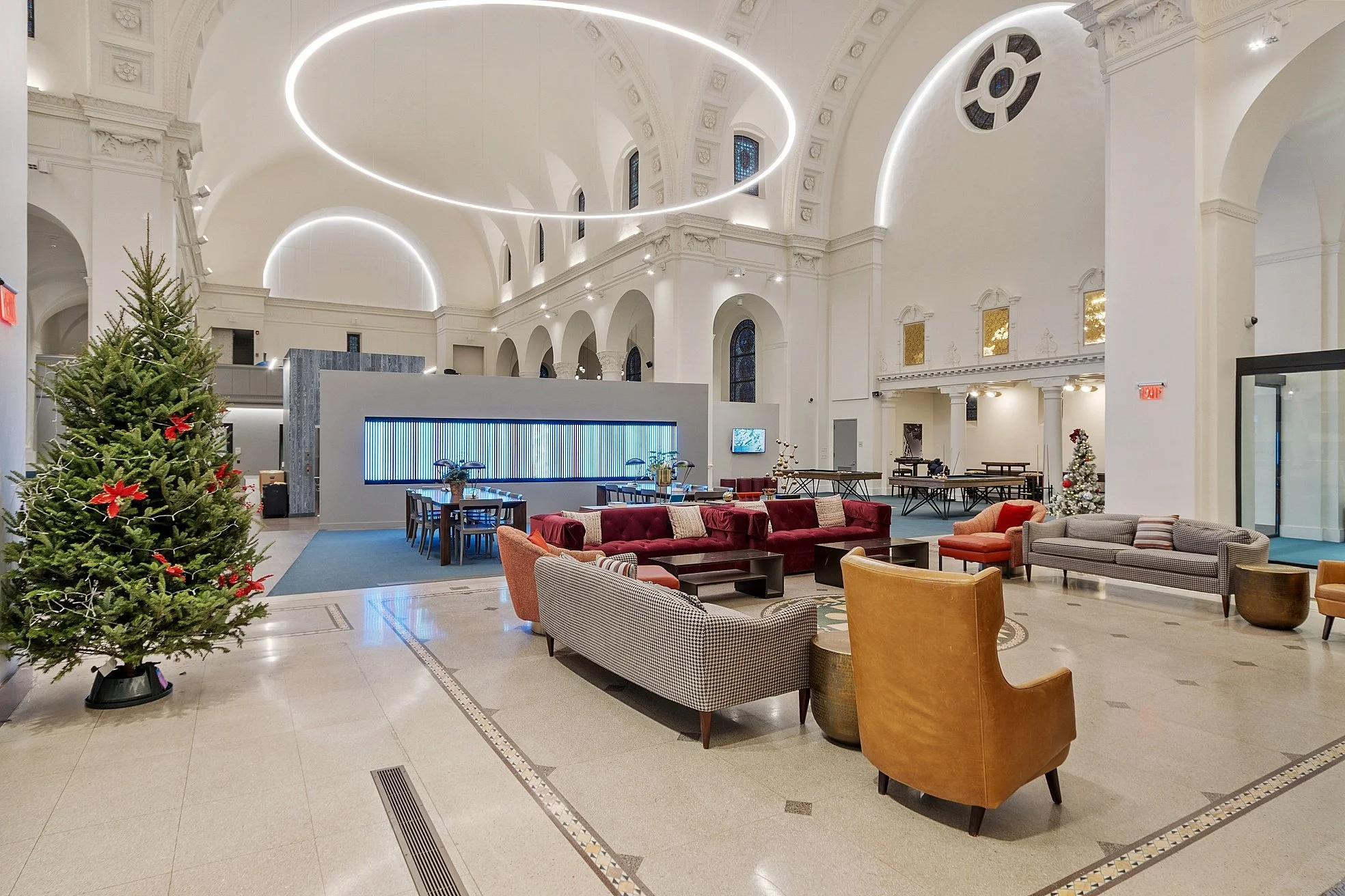 Elegant hotel lobby decorated for Christmas with Christmas trees, modern lighting, and comfortable seating areas.