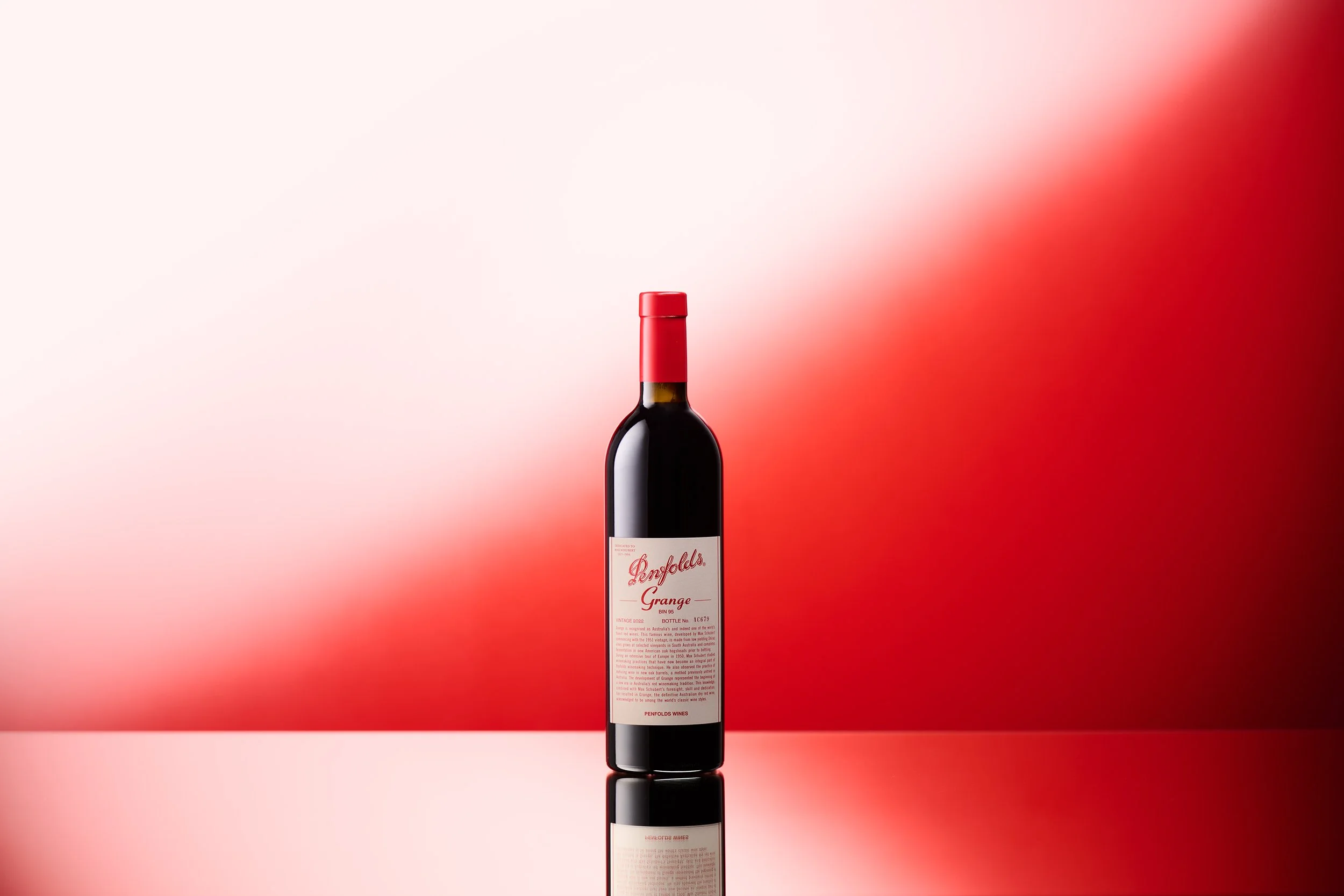 A bottle of Penfolds Grange 2022 on a red background.